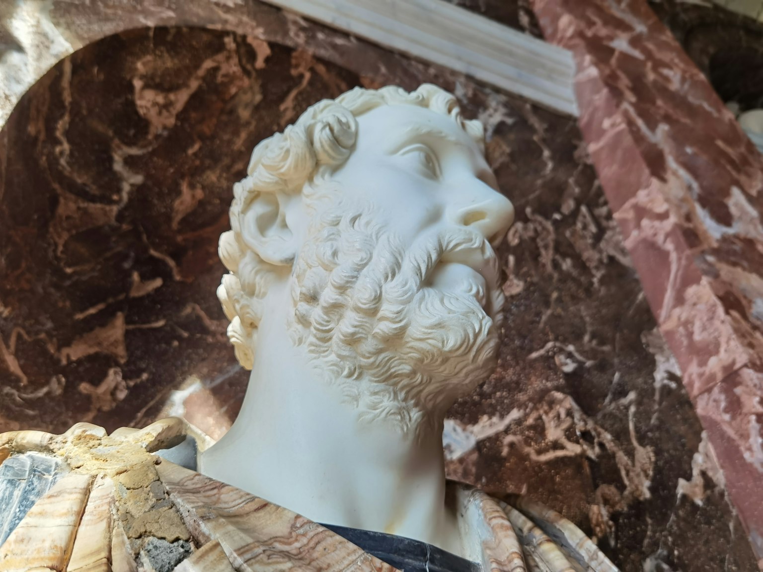 Scultura in marmo che rappresenta la testa di una figura romana antica di profilo