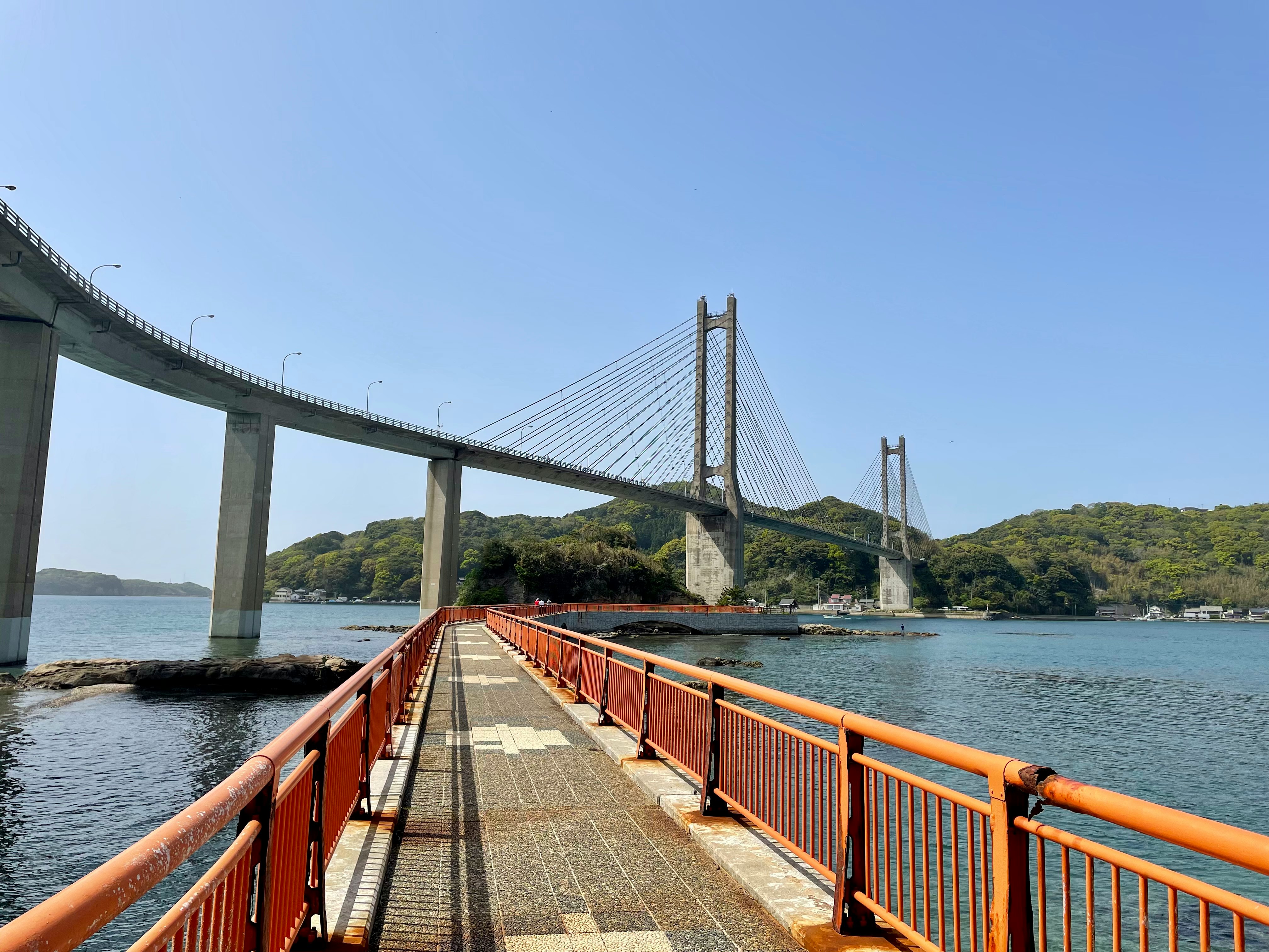 Passeggiata sul mare con ringhiere rosse e lungo ponte sospeso