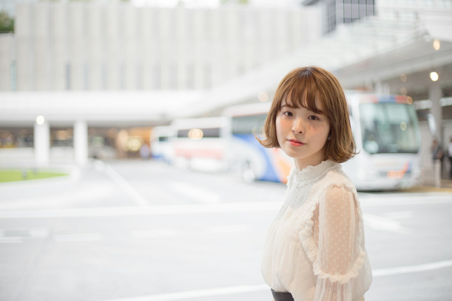 Woman smiling in a city setting with a bus stop in the background