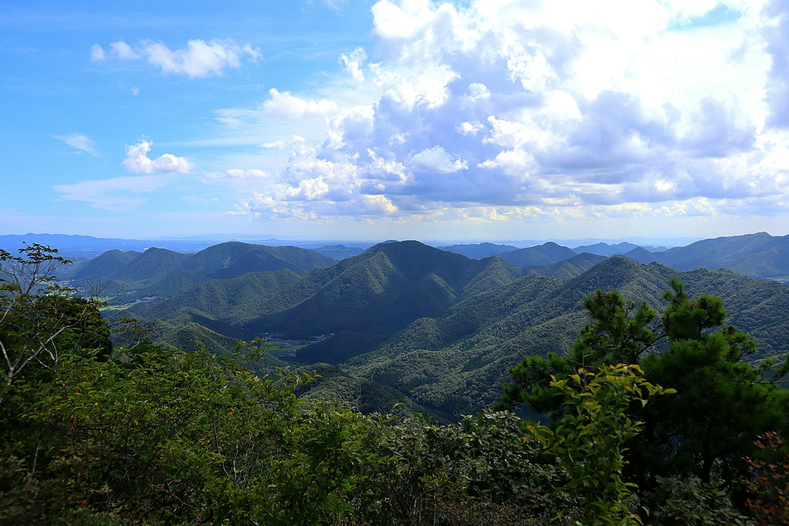 Vue expansive sur les montagnes et le ciel bleu Végétation luxuriante et nuages blancs