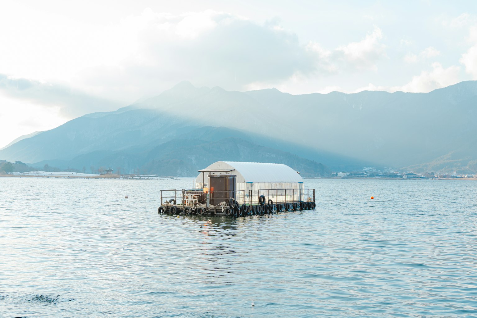Cabina bianca galleggiante sull'acqua con montagne sullo sfondo