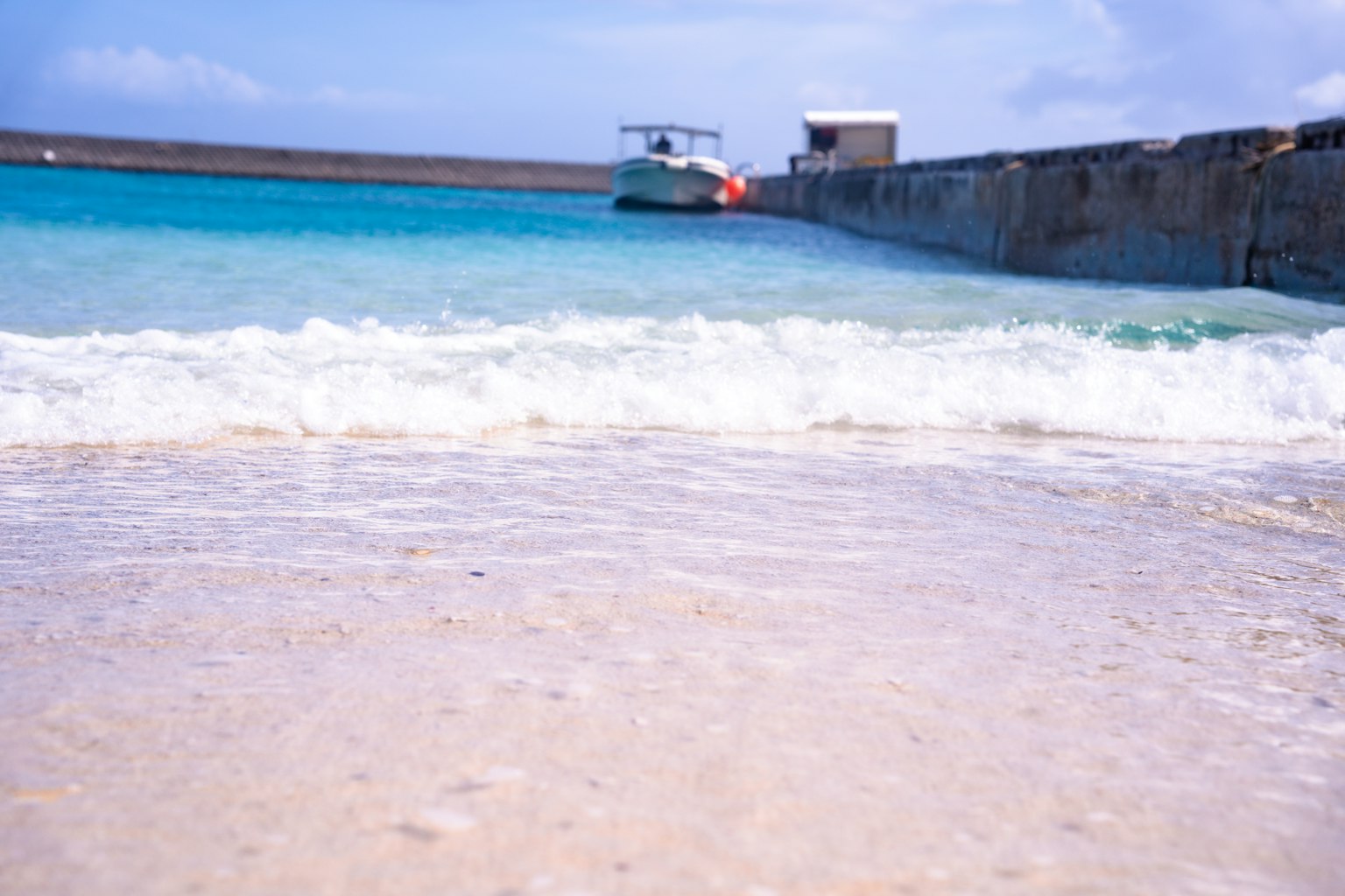 Spiaggia panoramica con onde leggere e una barca ormeggiata sulla riva