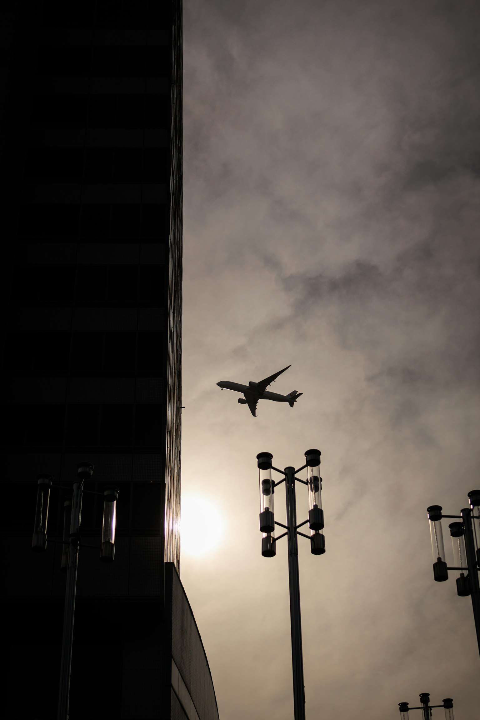 Aereo che vola davanti a un edificio in silhouette e al tramonto