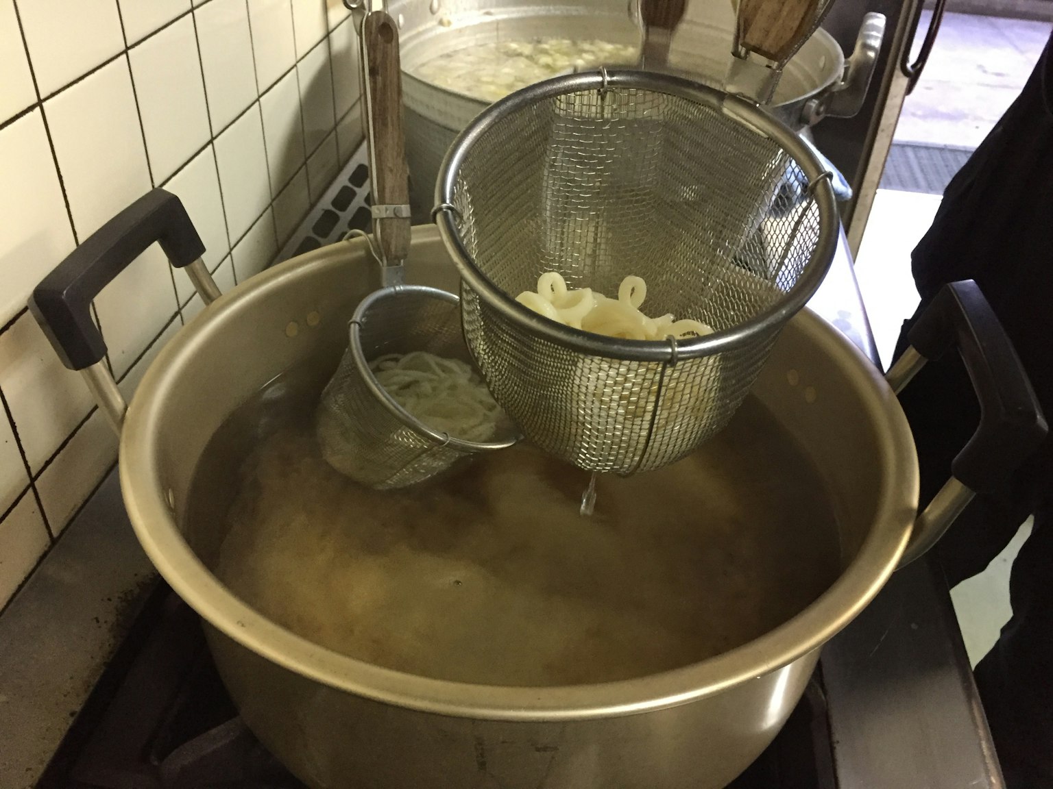 Escena de cocina con una olla hirviendo y un colador