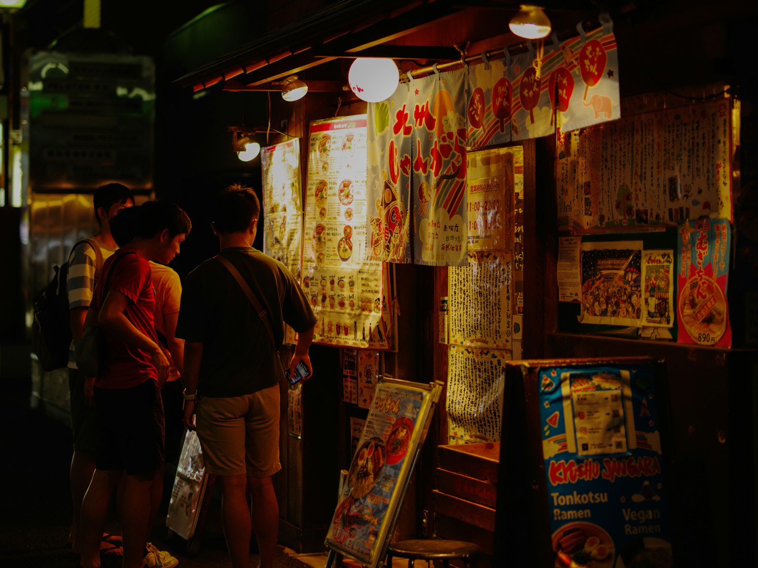 人們在夜市攤位前看菜單，旁邊有明亮的燈籠