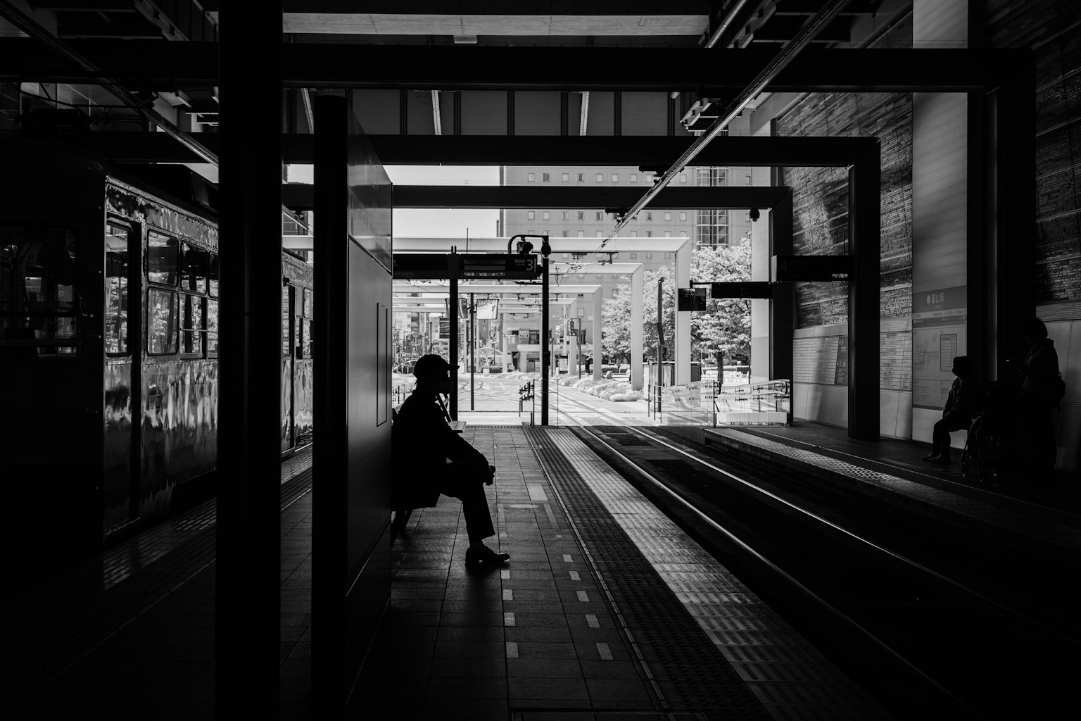 Silhouette di una persona seduta su una piattaforma in un'immagine in bianco e nero