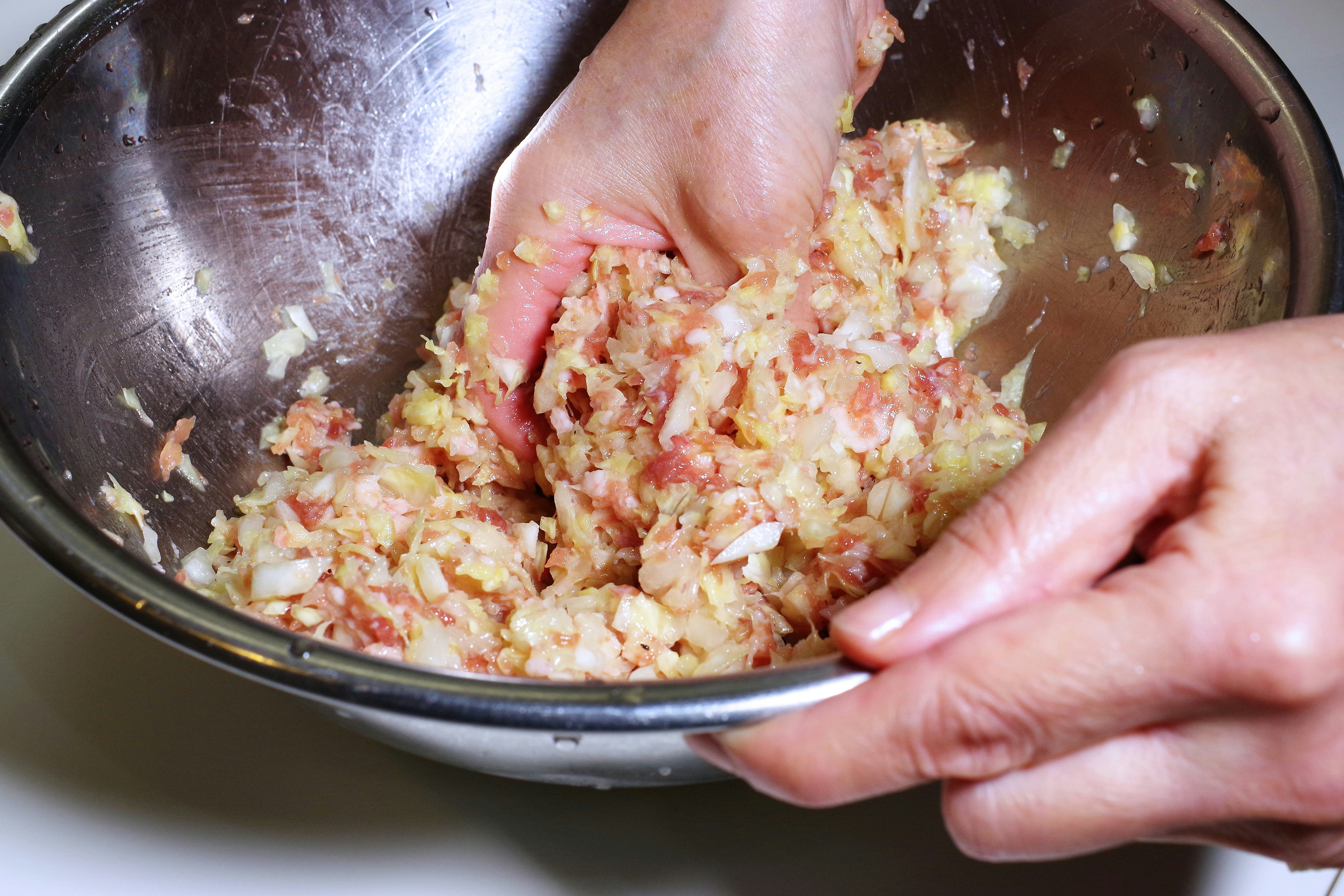 hands mixing chopped ingredients in a bowl