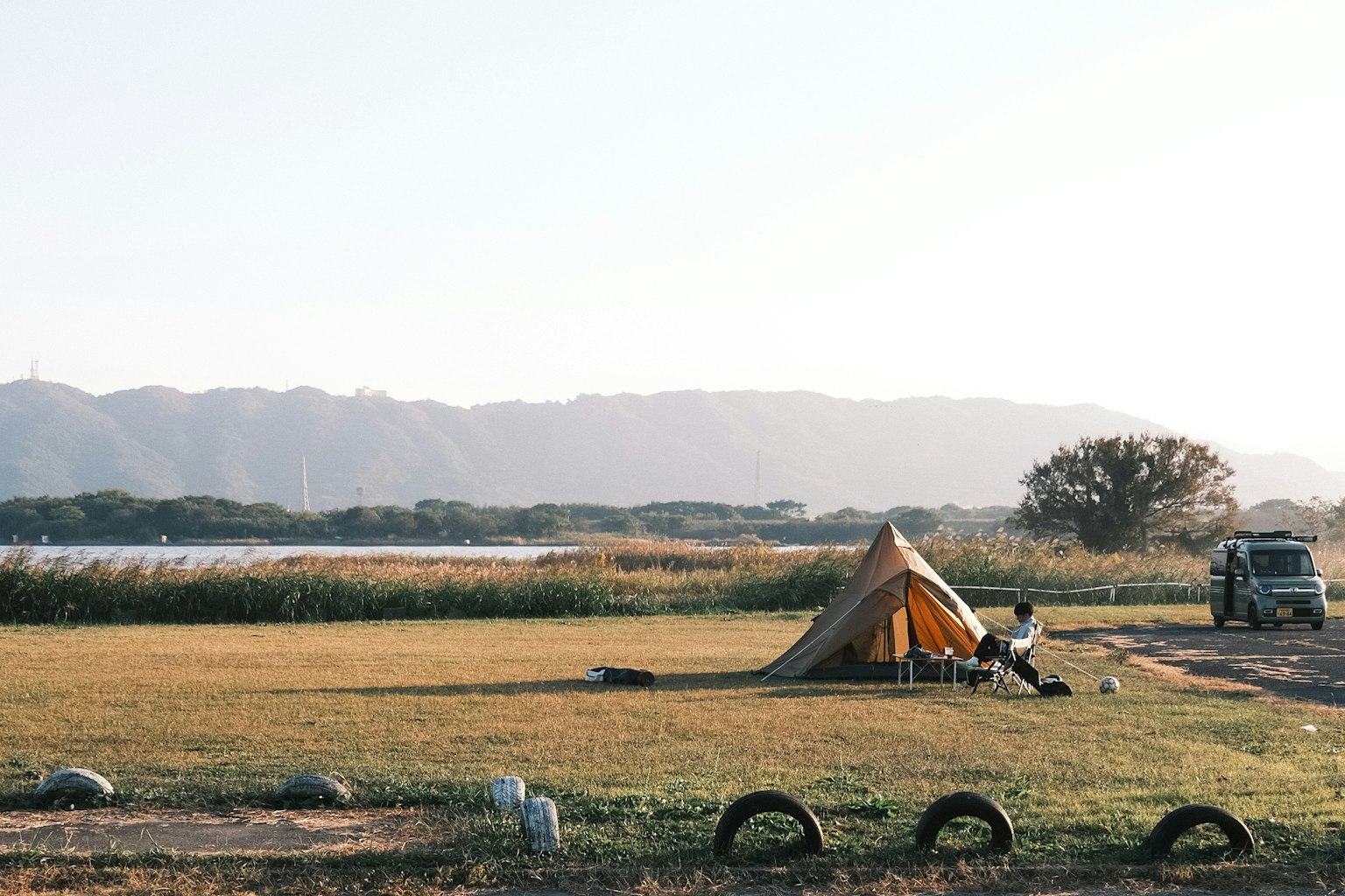 Una grande tenda sistemata in un'ampia area erbosa con natura circostante