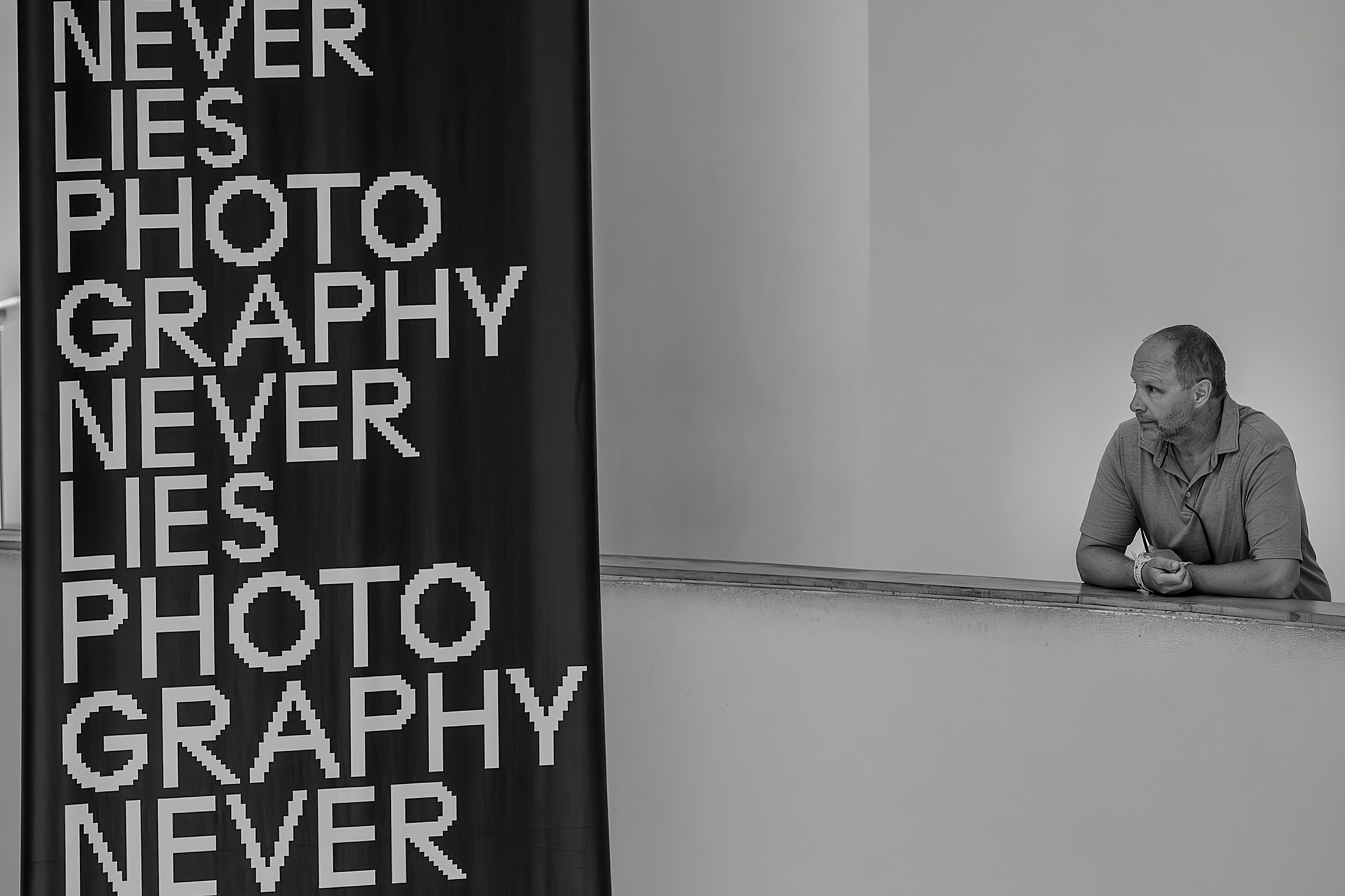 a seated person beside a “NEVER LIES PHOTO GRAPHY” text panel