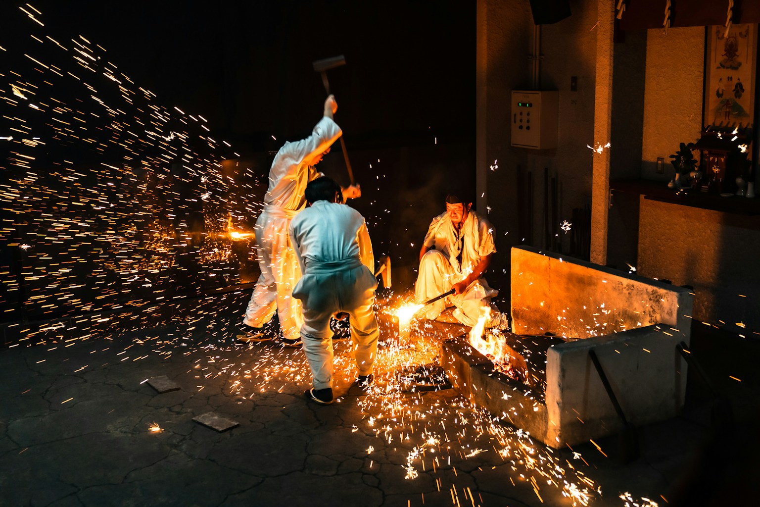 Artisans forging metal with sparks flying in a dark workshop