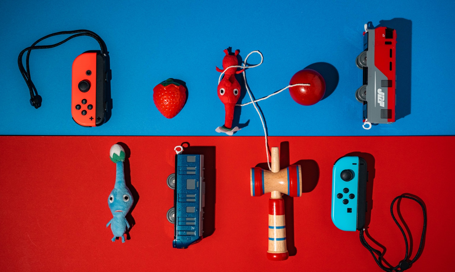 Controller di gioco e personaggi giocattolo disposti su uno sfondo blu e rosso