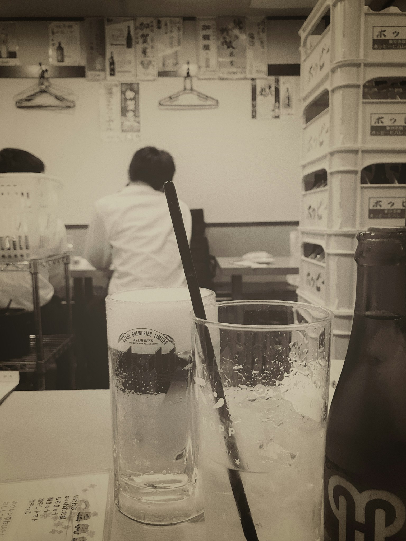 A view of a restaurant staff member behind the counter with glasses on the table