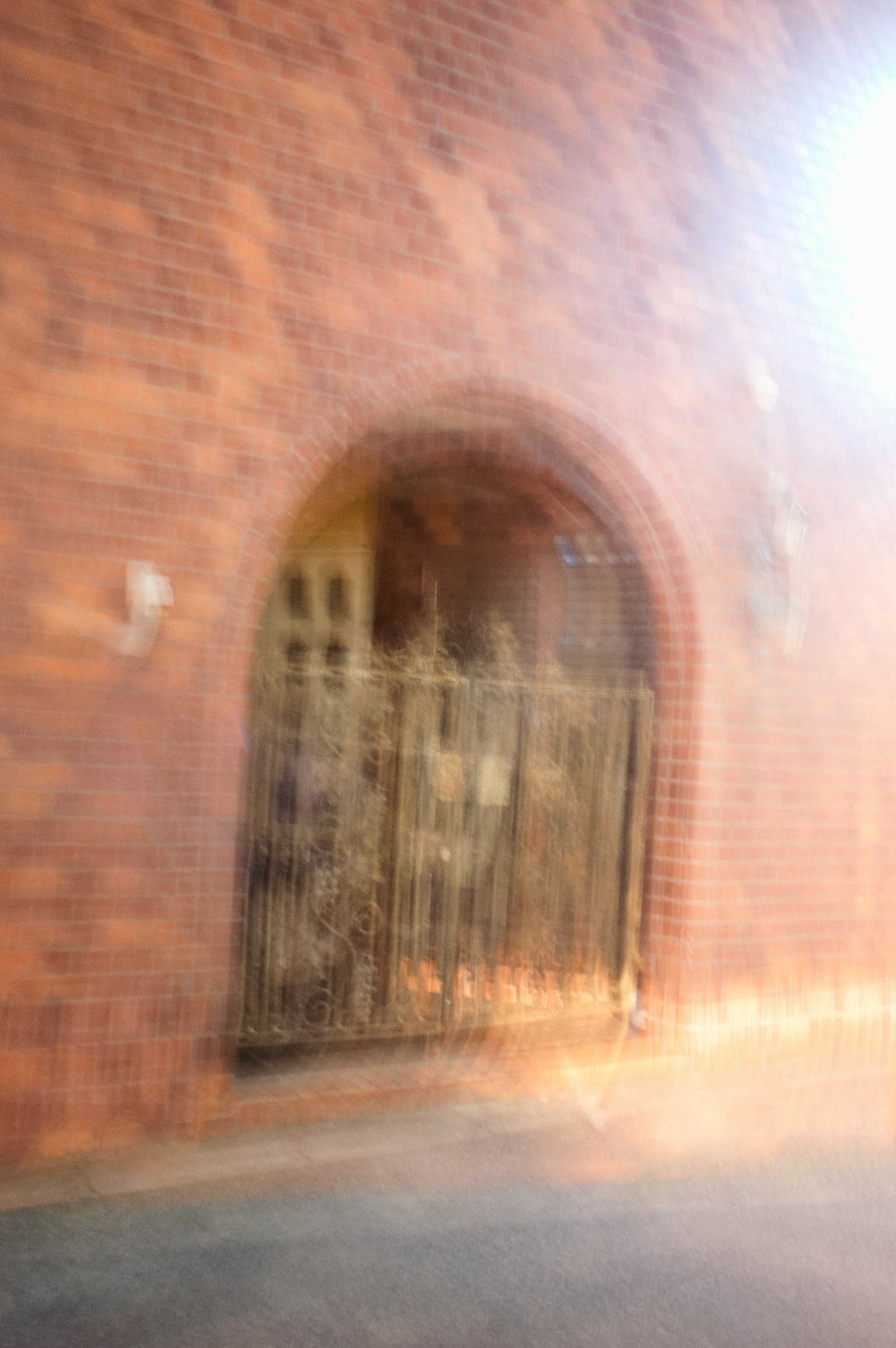 Blurred brick wall with an arched entrance and a metal gate