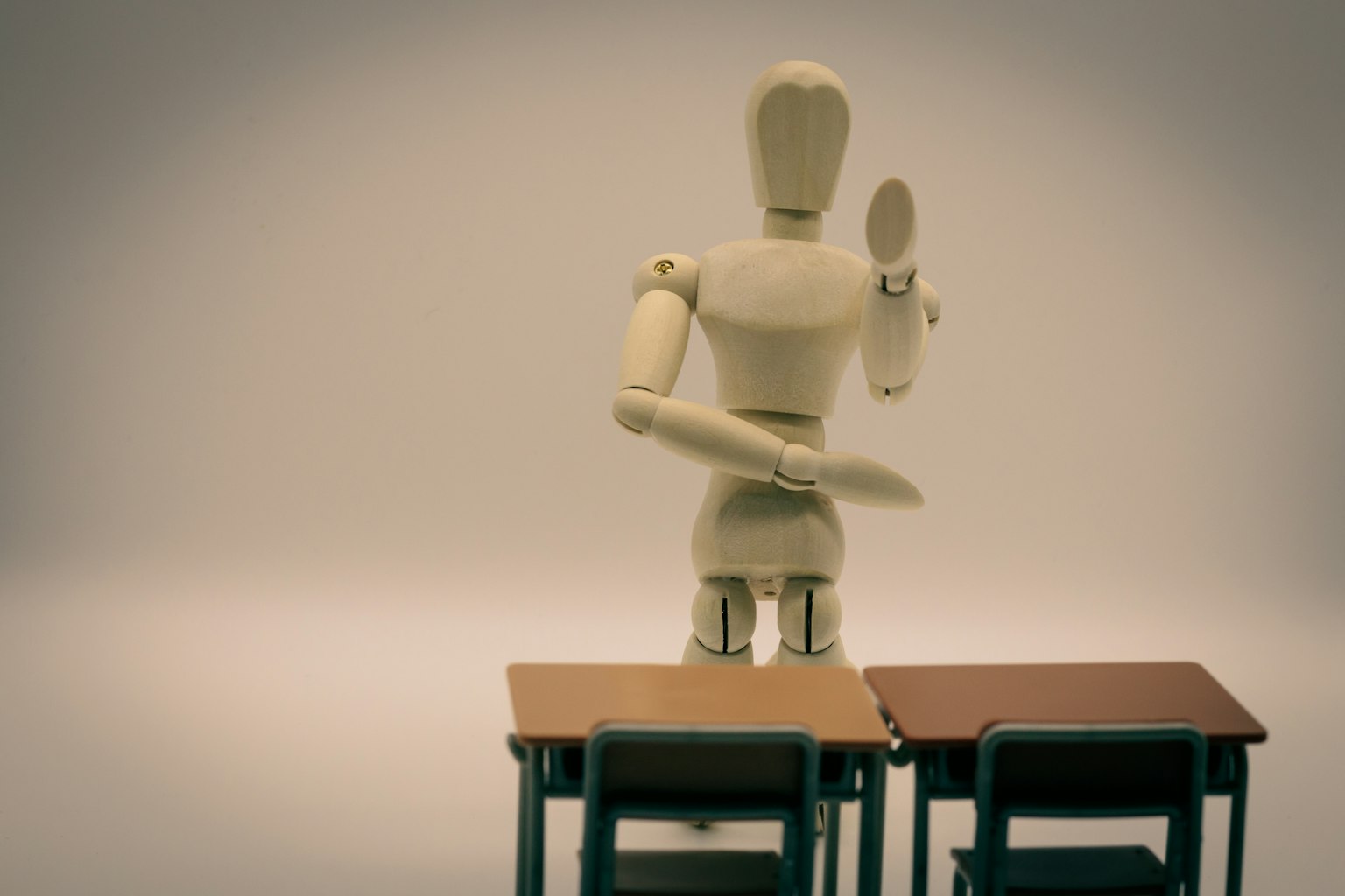 A wooden mannequin posing in front of two tables
