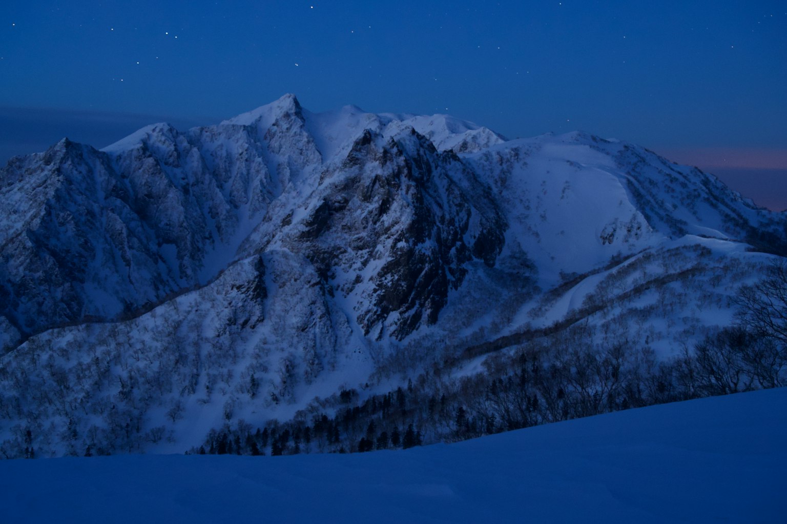 Stunning view of snowy mountains at night with a blue sky