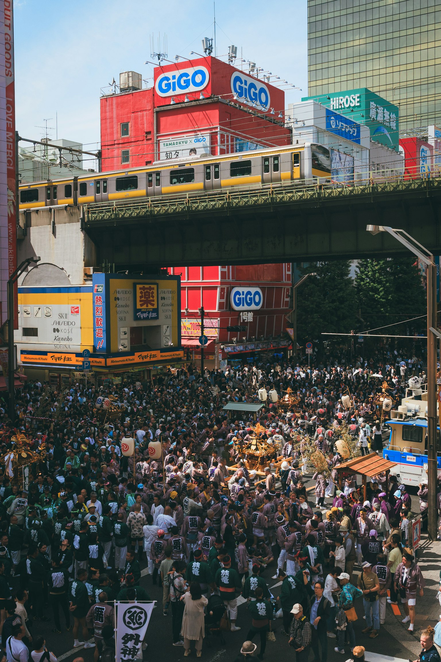Folla che si raduna in una vivace scena urbana con binari sopraelevati e pubblicità colorate