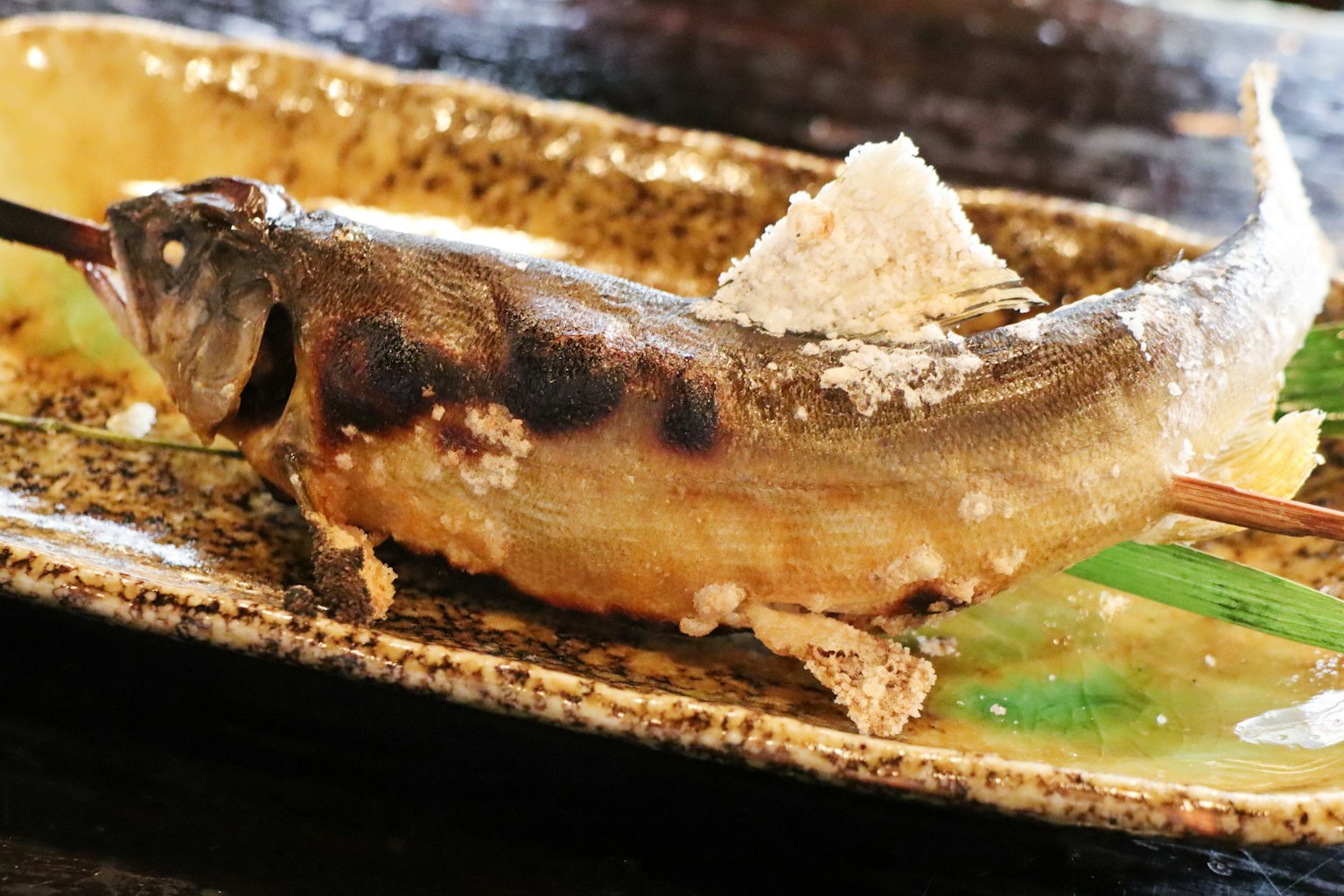 Pesce alla griglia su uno spiedino servito su un piatto decorativo