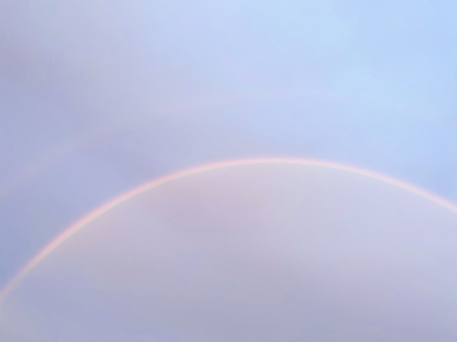Arc de rainbow pâle dans un ciel bleu clair