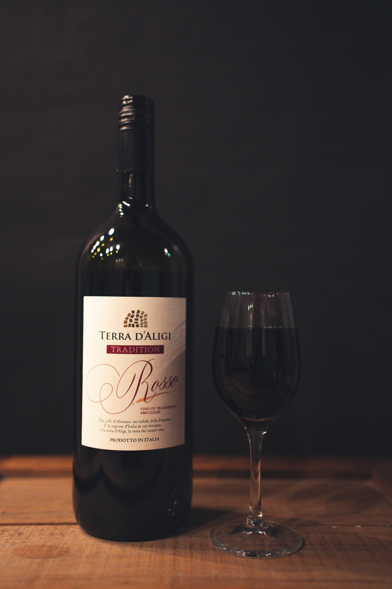 Une bouteille de vin rouge et un verre sur une table en bois