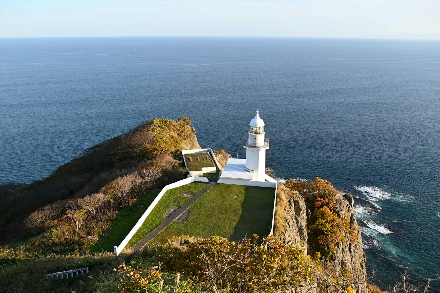 Un faro bianco con un giardino verde che si affaccia sull'oceano