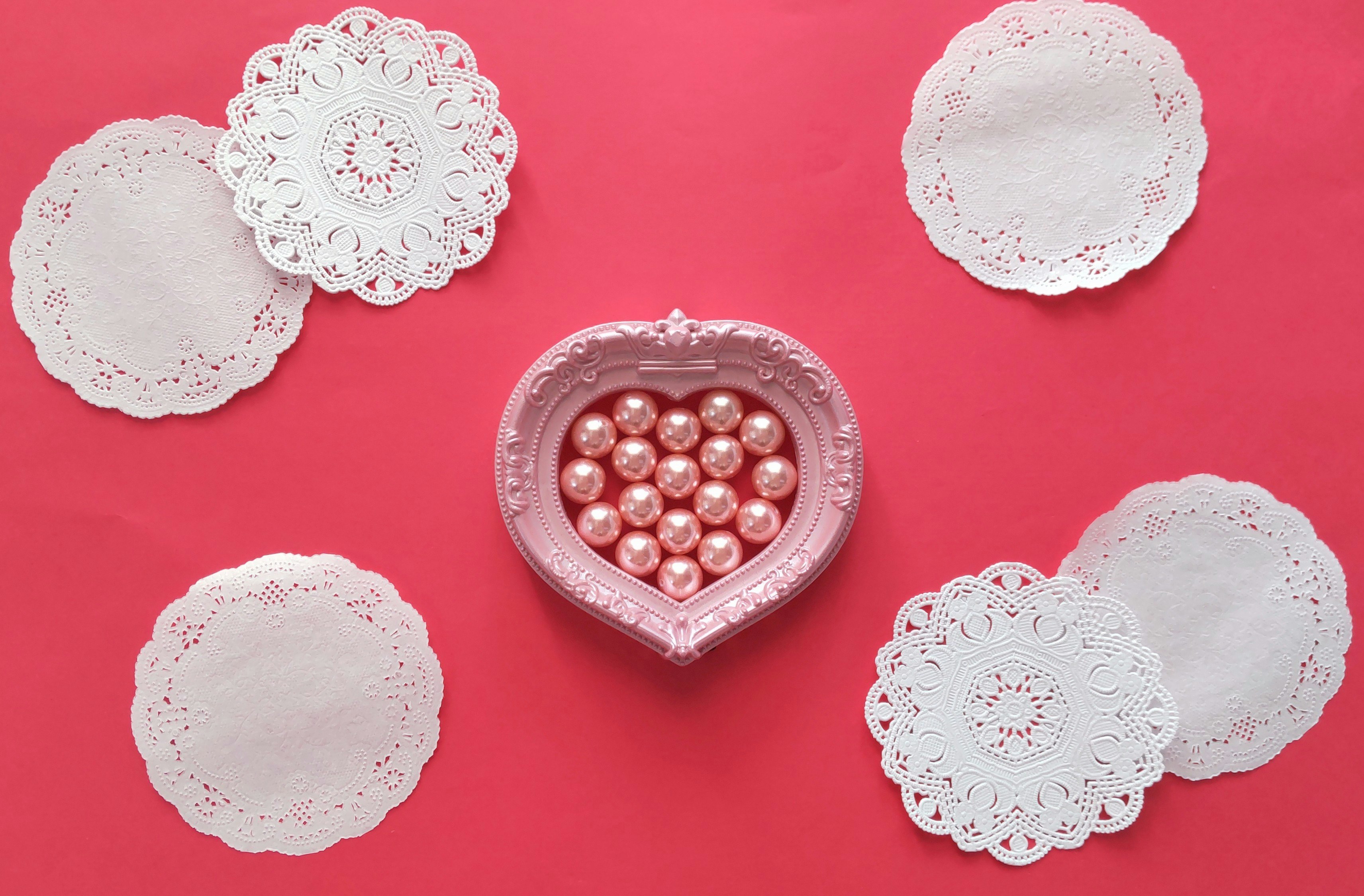 Valentine decor with a red heart-shaped box, pearls, and lace paper
