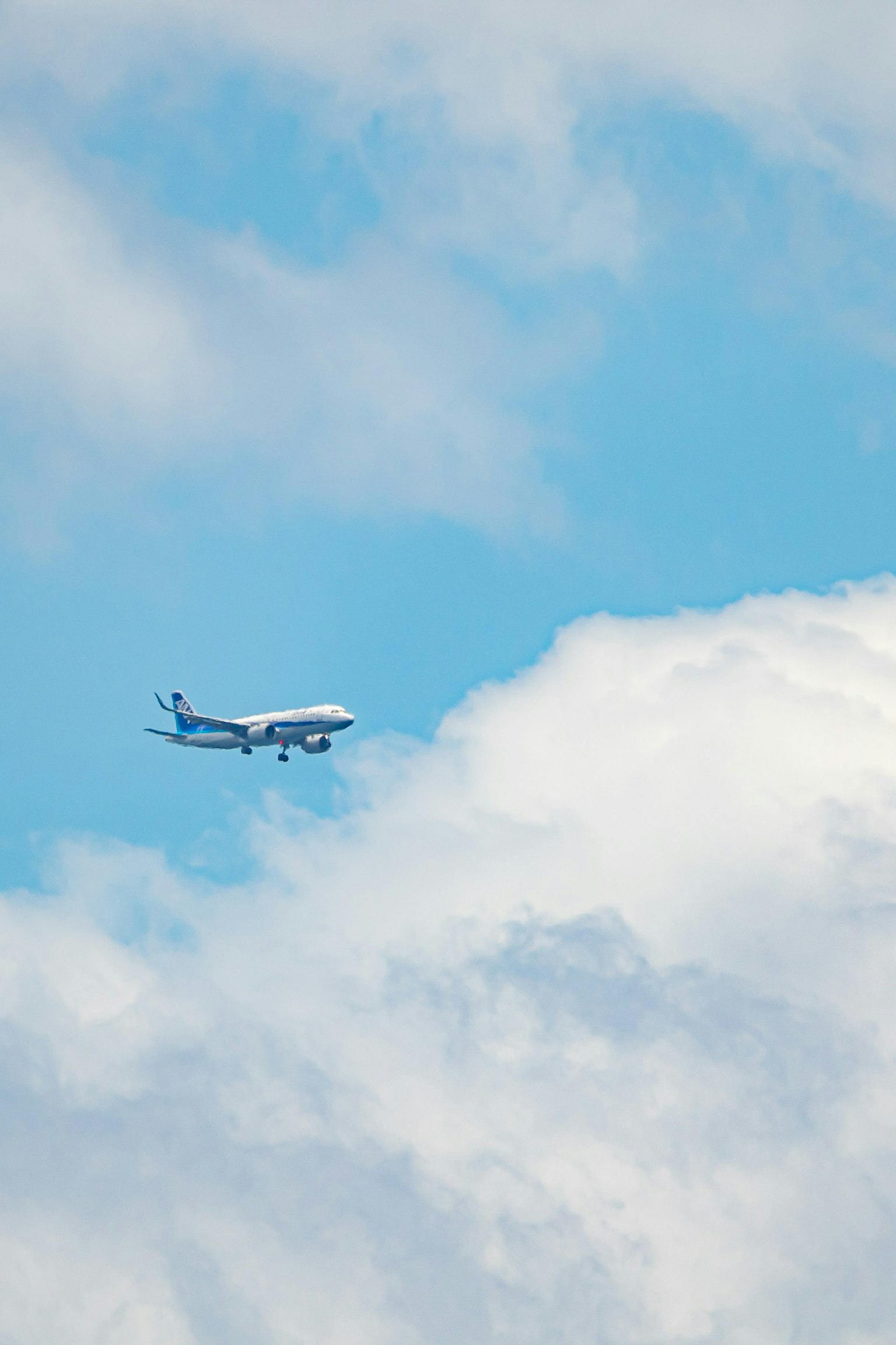Pesawat terbang di langit biru dengan awan putih