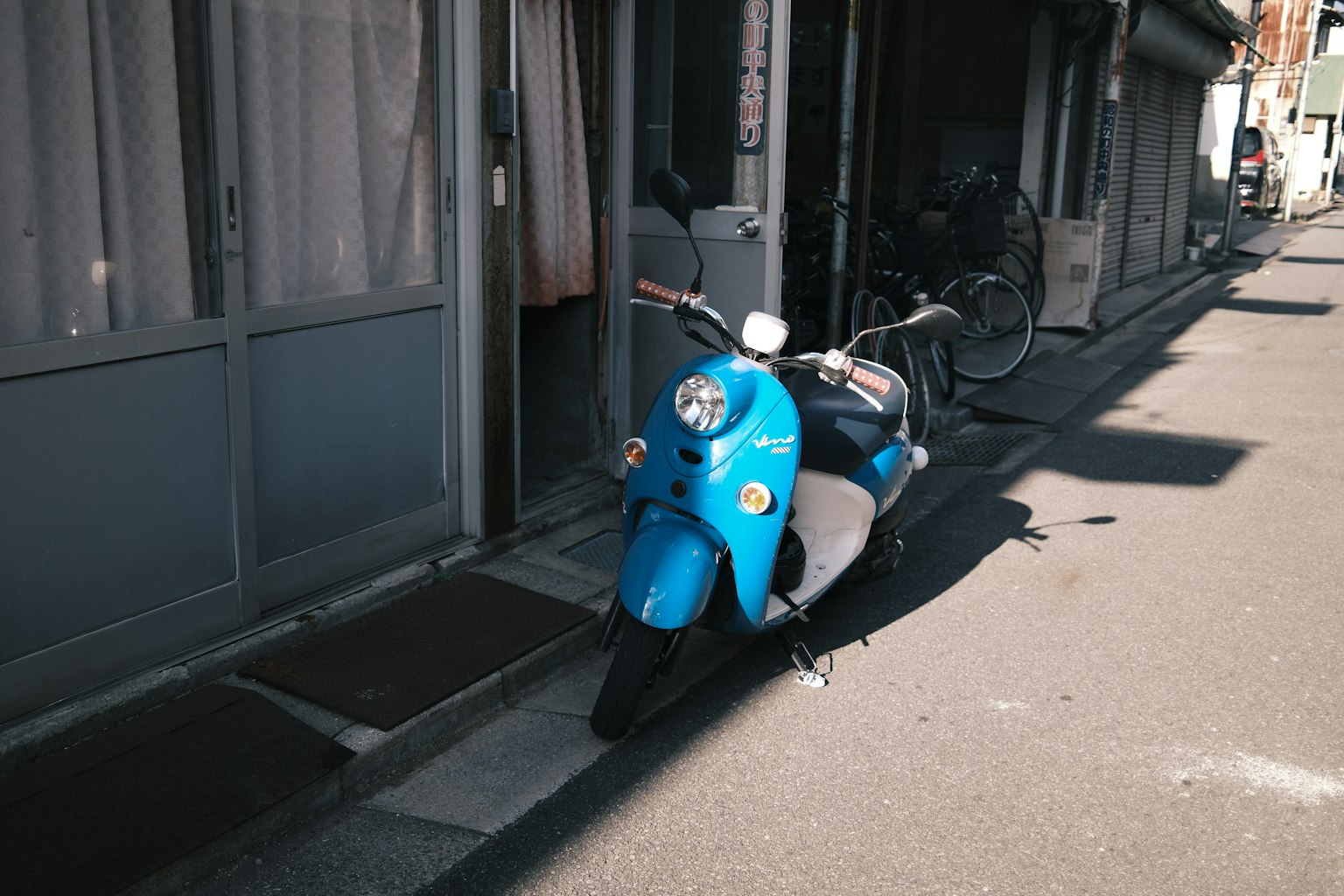 青いスクーターが狭い通りに停まっている