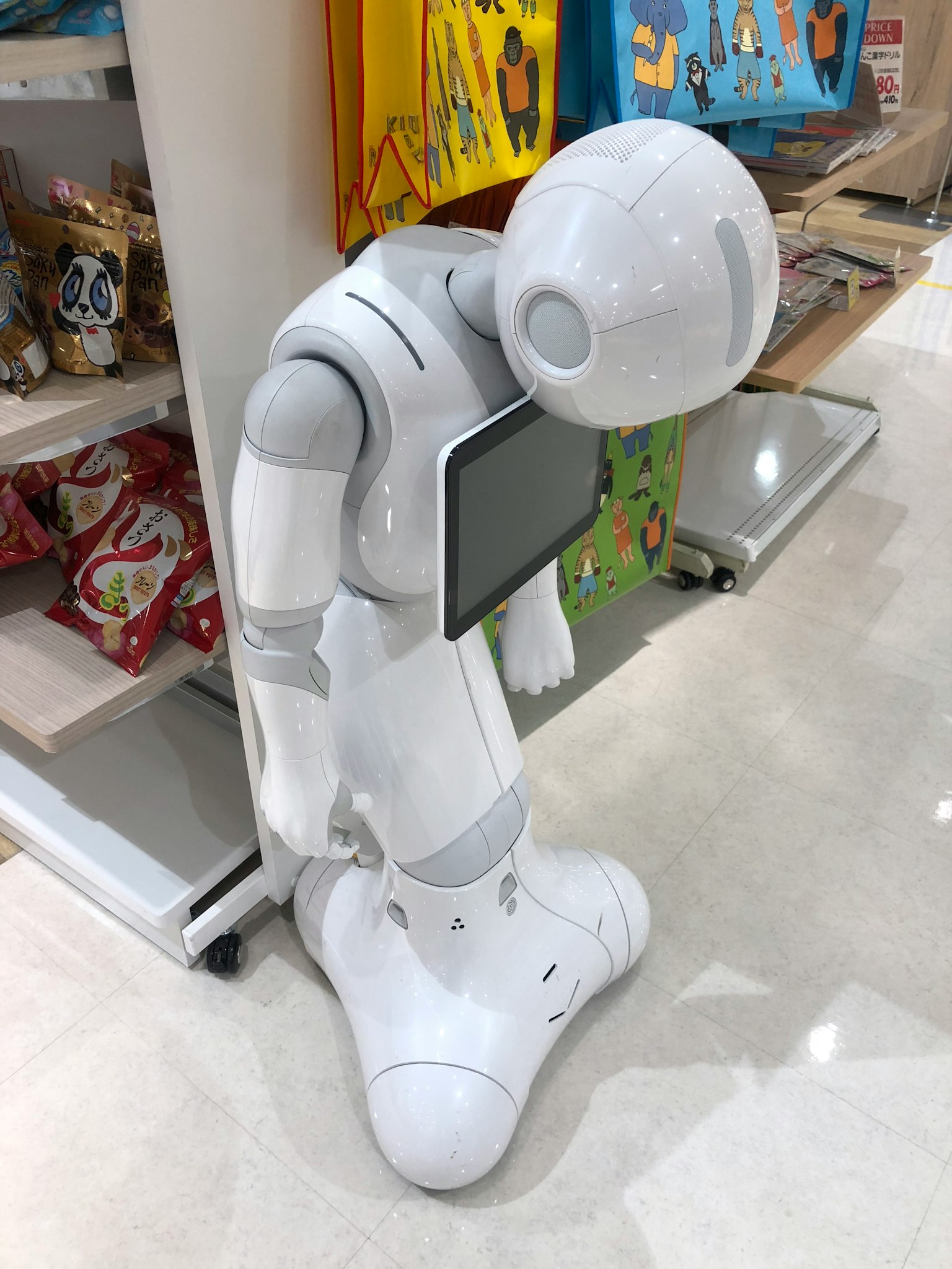 一個白色機器人向前彎曲，手持平板電腦