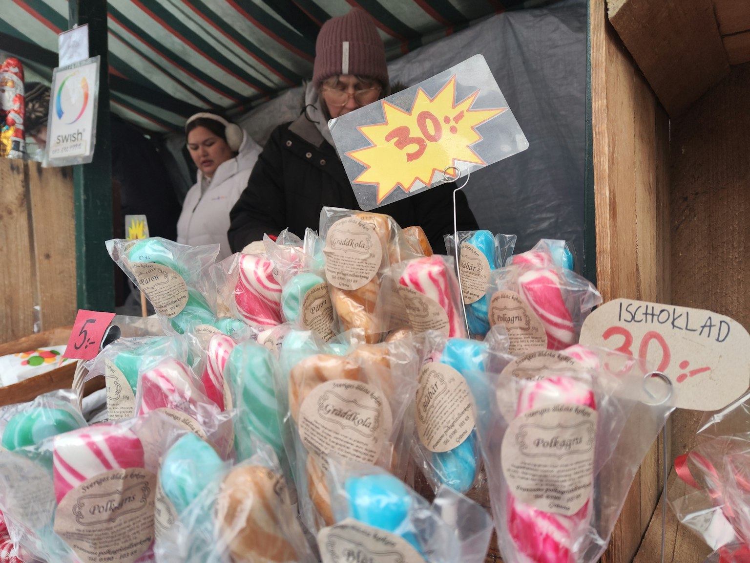 Bonbons colorés exposés sur un stand de marché avec deux femmes en arrière-plan