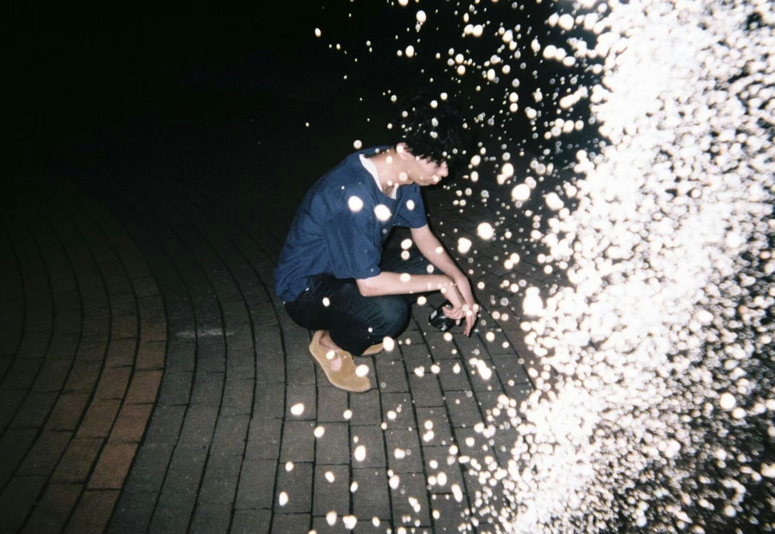 Une personne tendant la main au milieu de particules lumineuses sur un sol de nuit
