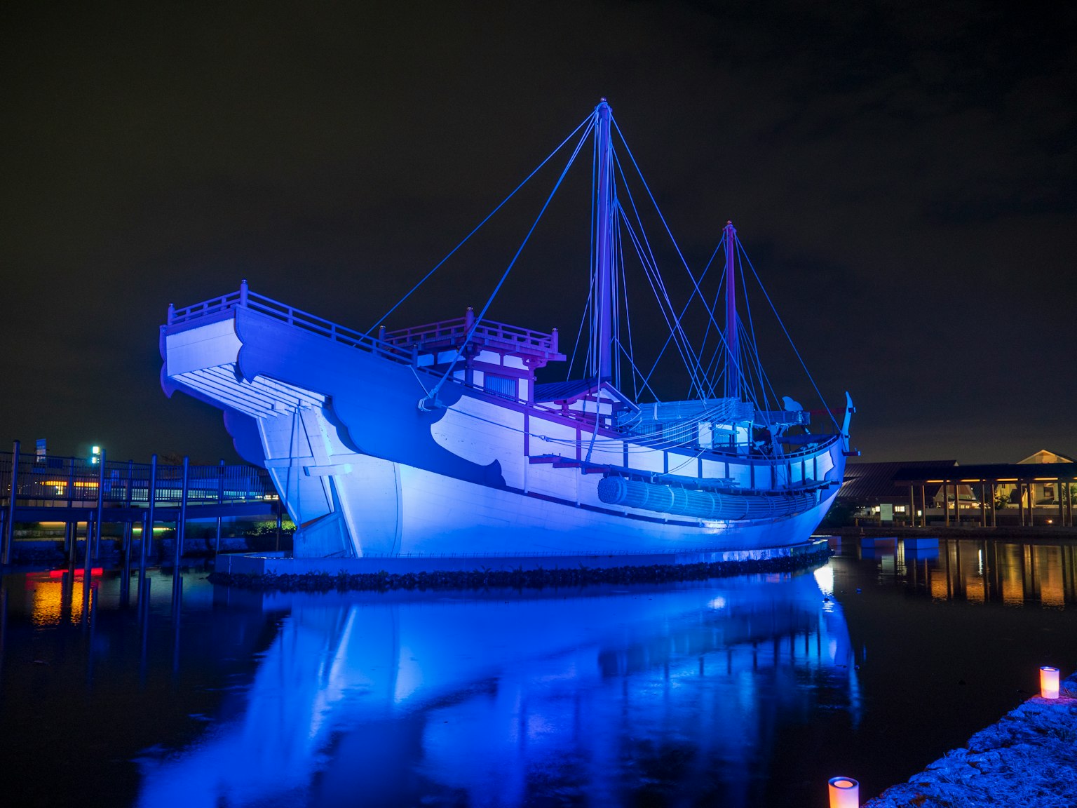 Un bateau illuminé par une lumière bleue flottant tranquillement dans le port la nuit