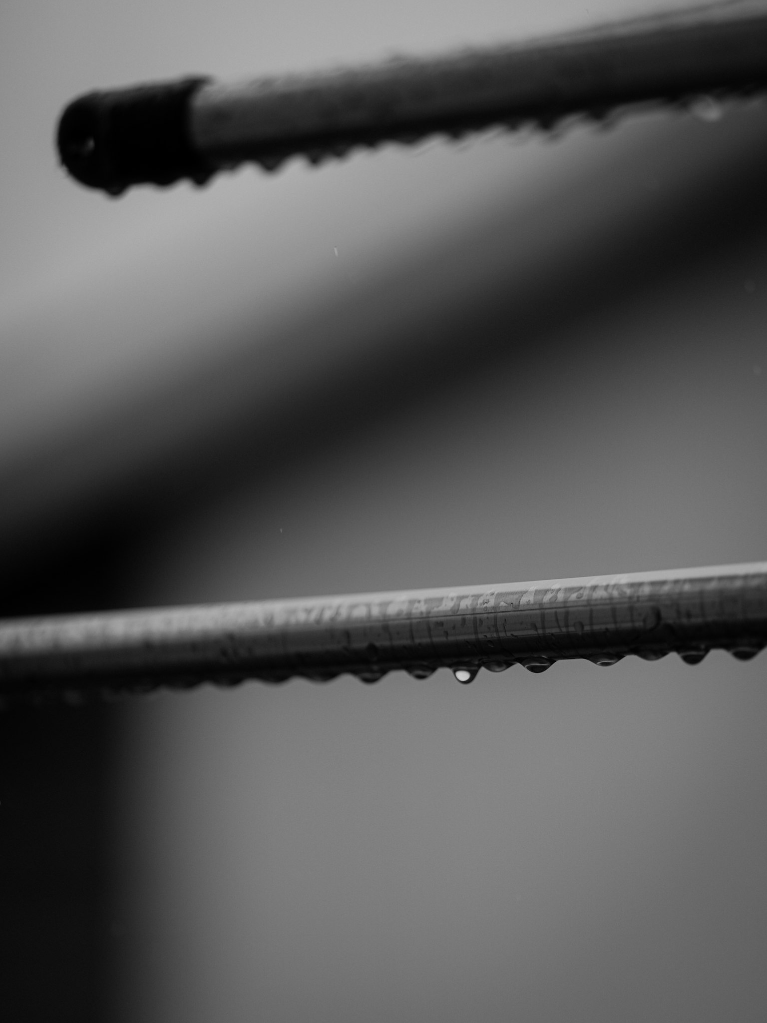 黒と白の背景に水滴がついた金属の棒