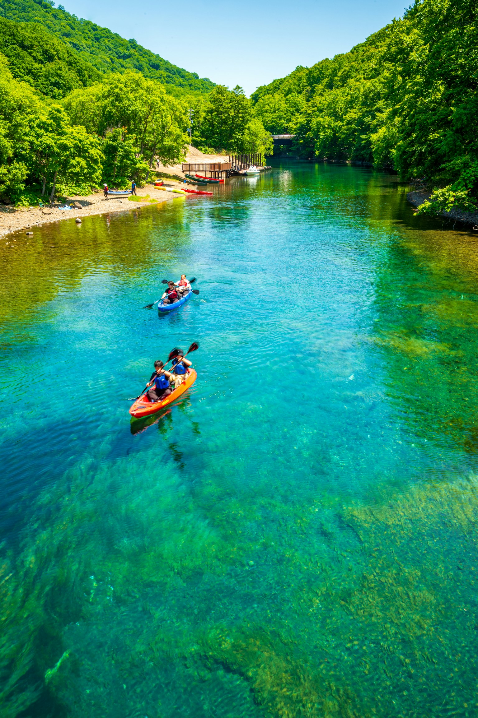 Personas en kayak en un río azul claro rodeado de montañas verdes