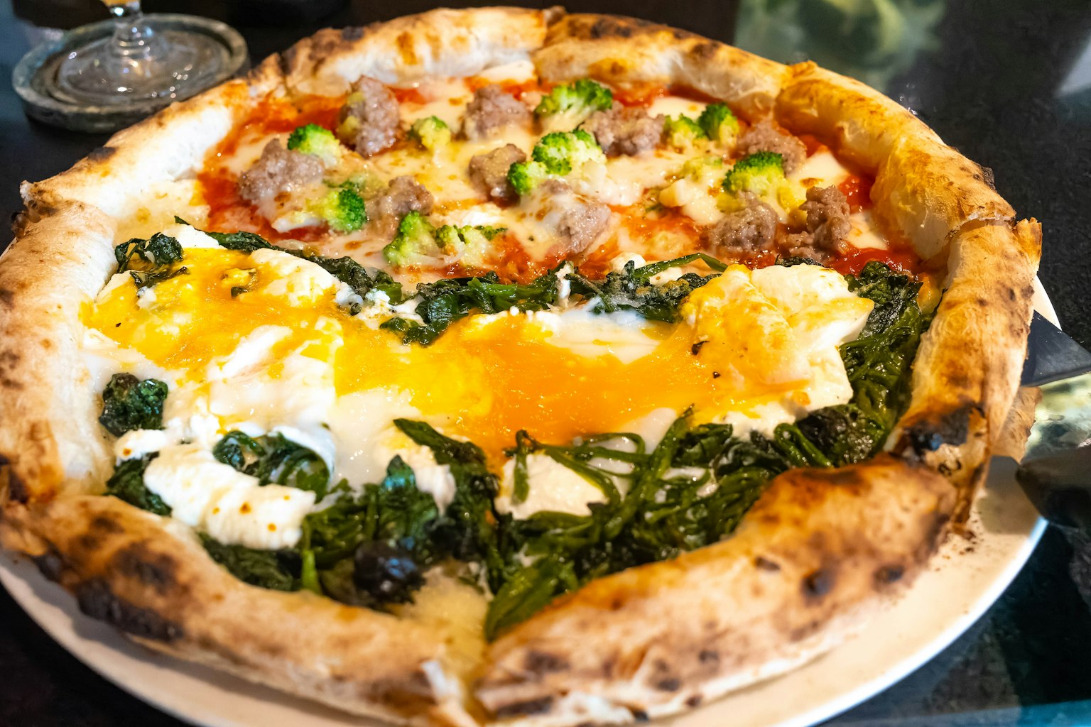 Pizza délicieuse avec deux moitiés distinctes présentant des garnitures de saucisse et de légumes verts avec des œufs