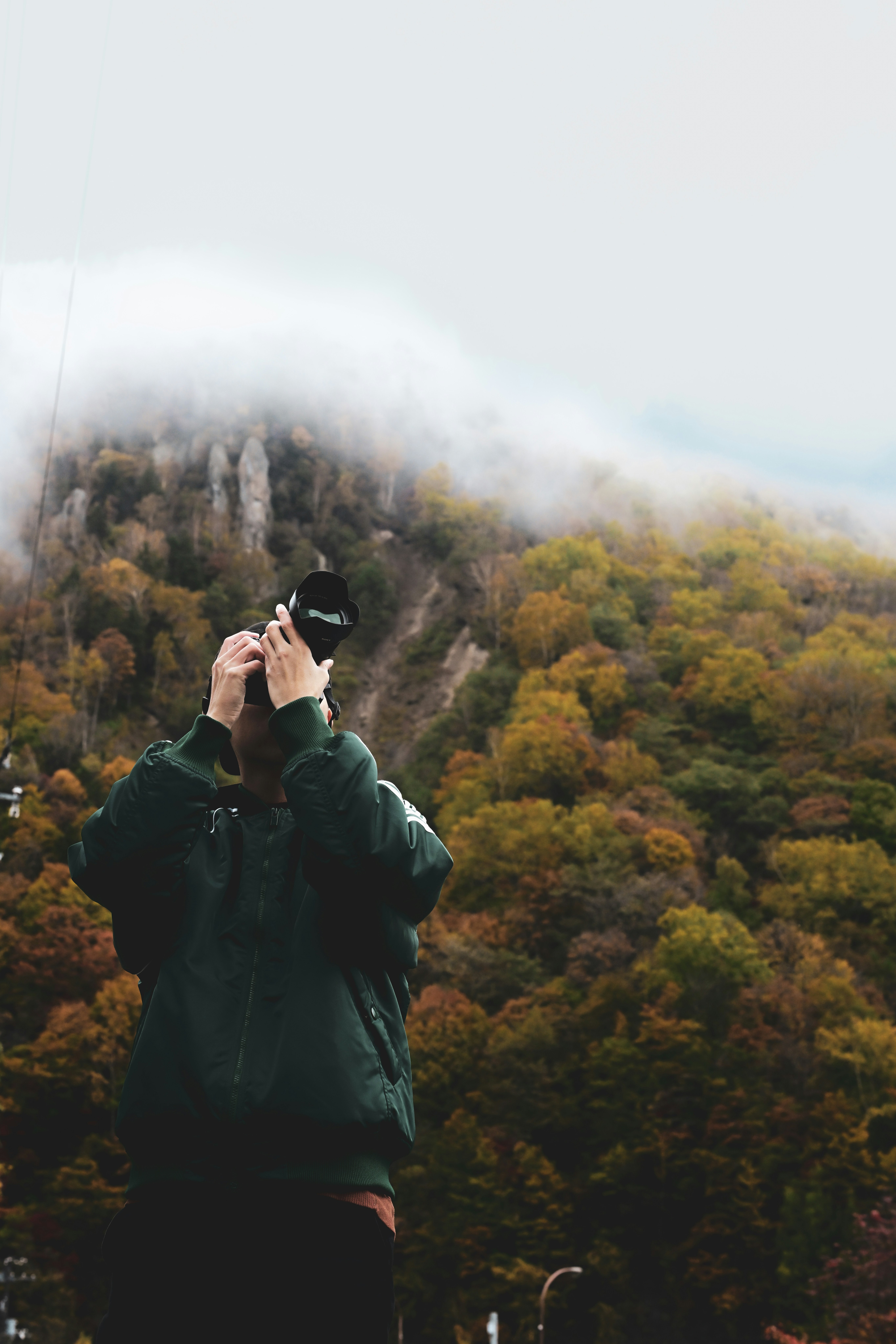 紅葉の山並みを見上げる人物のシルエット