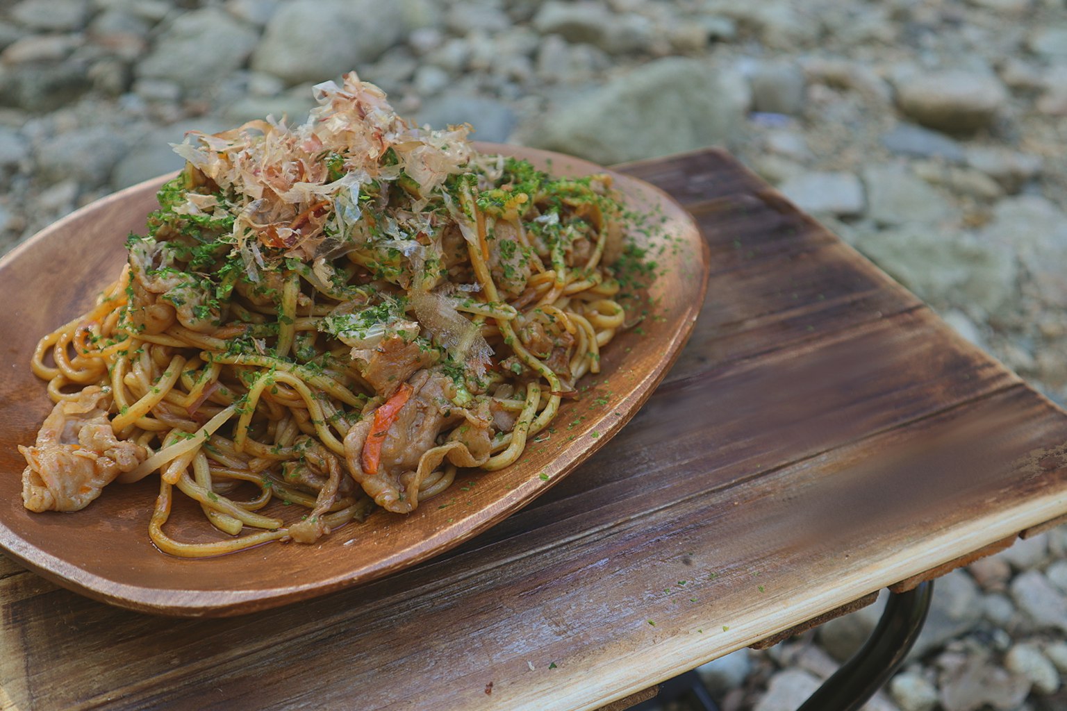 Noodles saltati serviti su un piatto di legno in un ambiente naturale