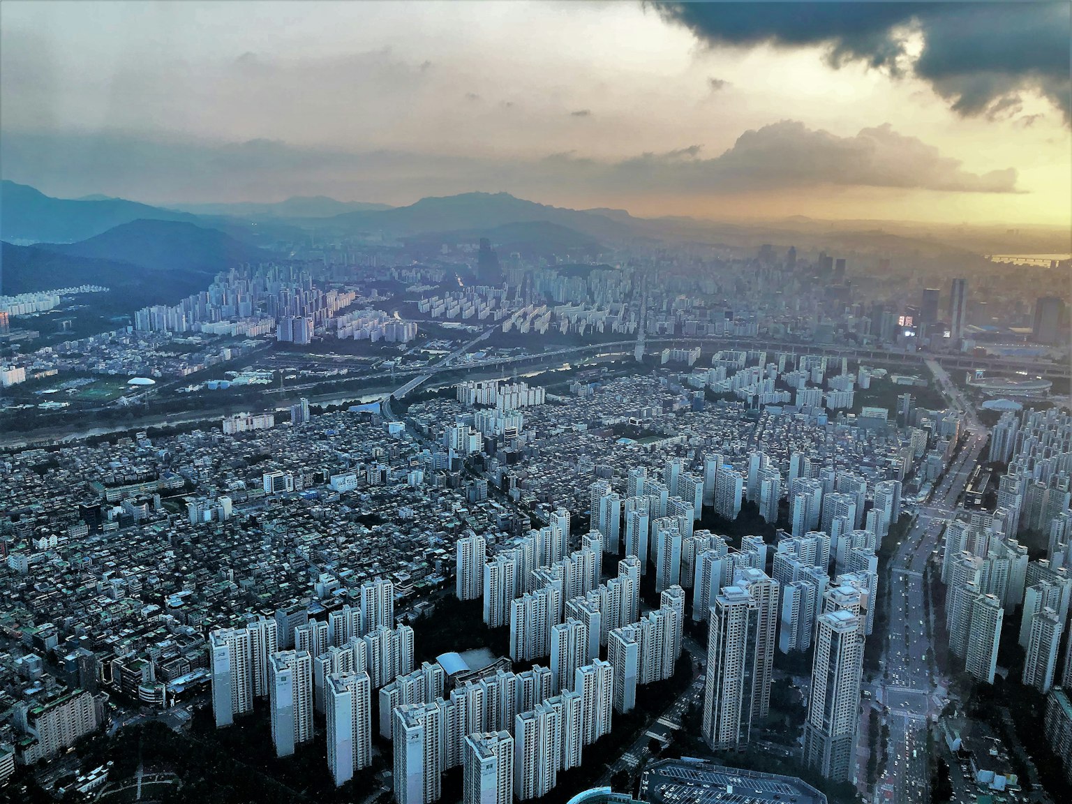 Vista aérea de edificios altos urbanos con montañas al fondo durante el atardecer