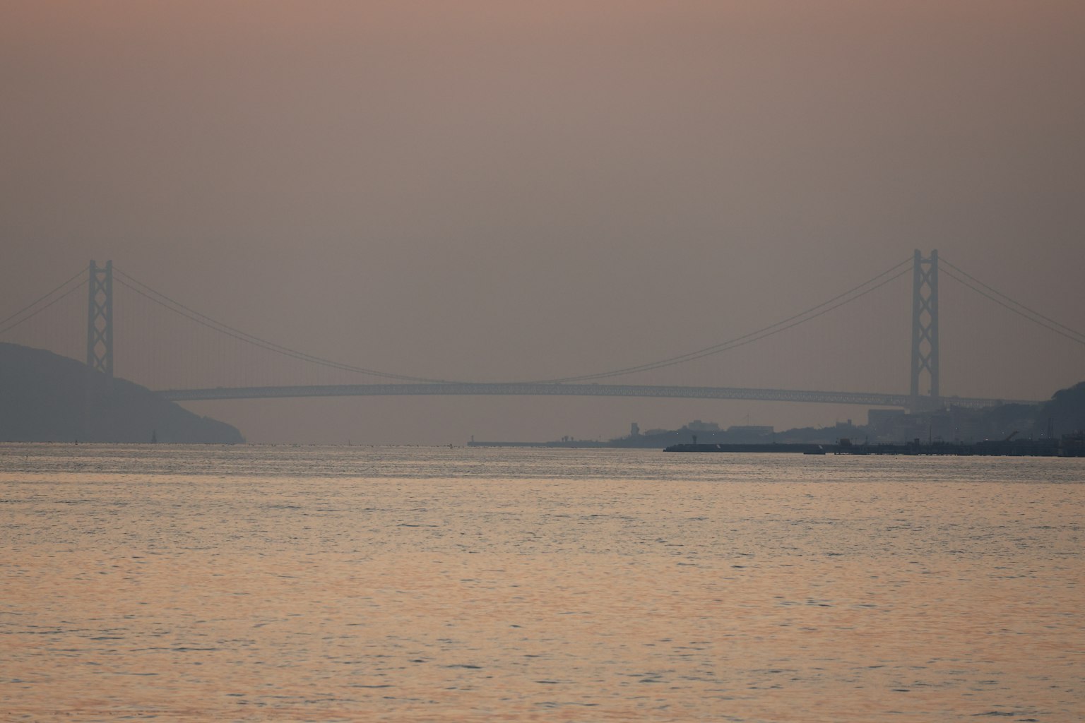 Silhouette of a bridge over a river at dusk