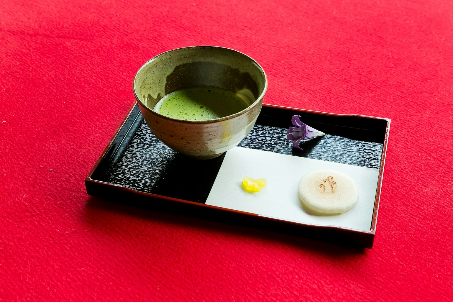 Matcha et sucreries traditionnelles sur un plateau noir avec un fond rouge