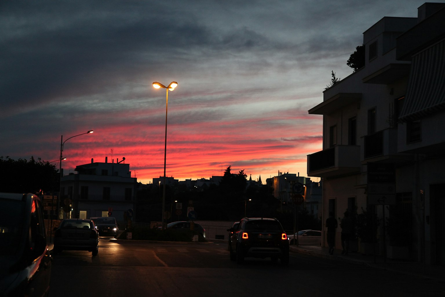 Cielo de atardecer colorido con siluetas de edificios y coches