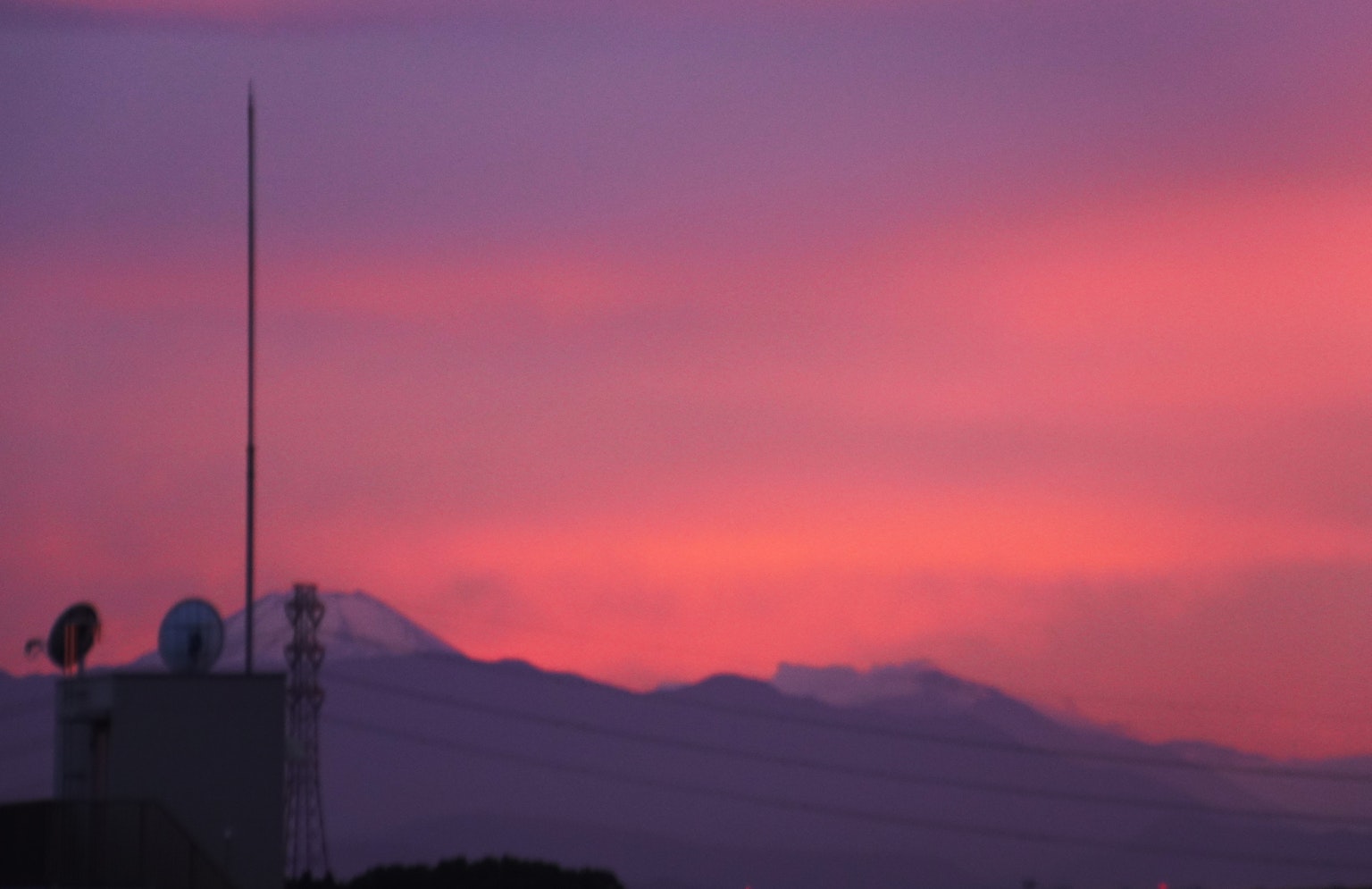 Silhouette di un edificio contro un cielo al tramonto con montagne