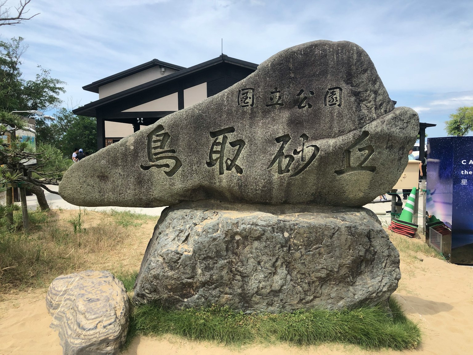 Stone monument at Tottori Sand Dunes with a building in the background