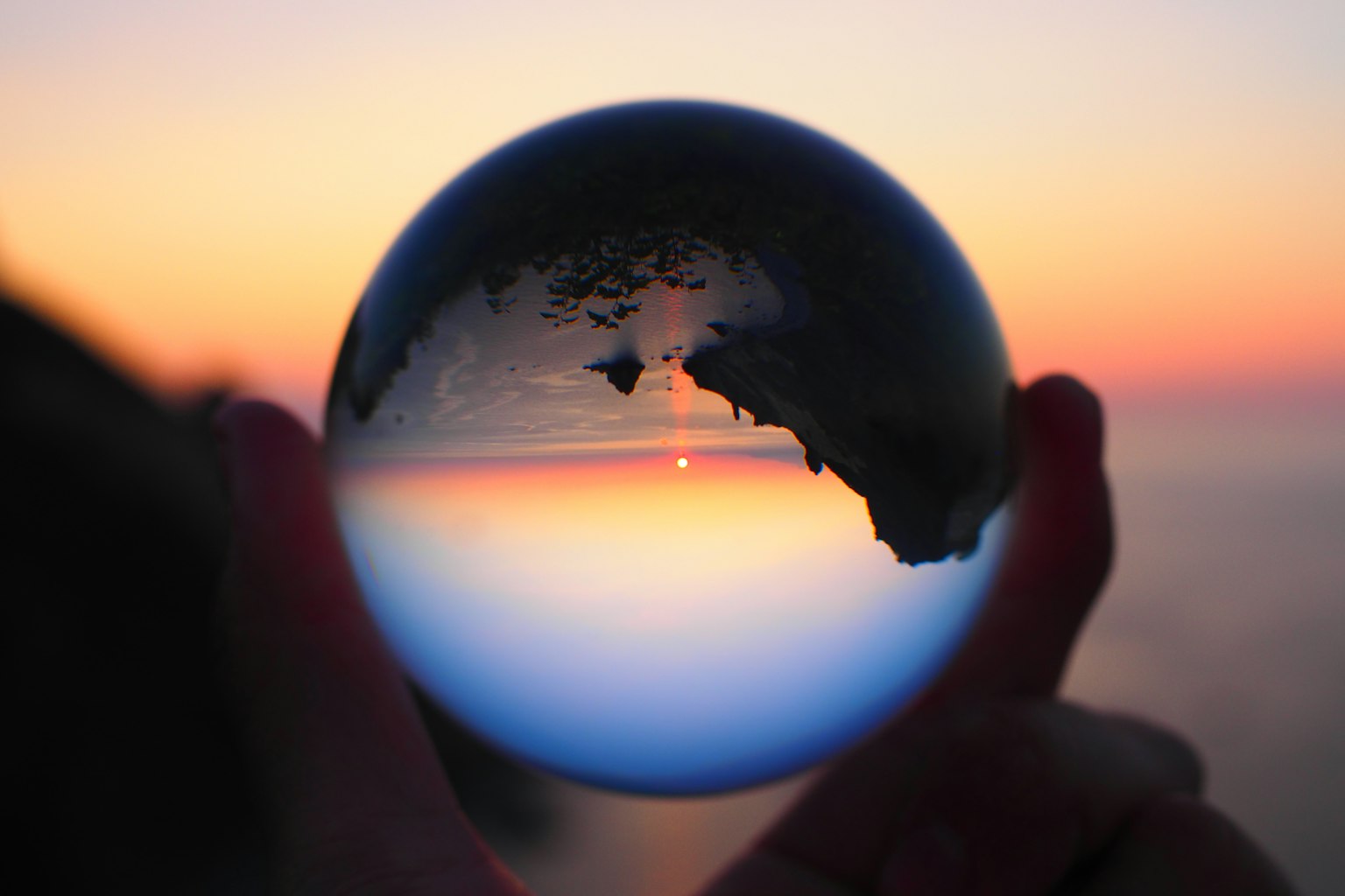 Palla di cristallo che riflette il gradiente del tramonto e l'oceano
