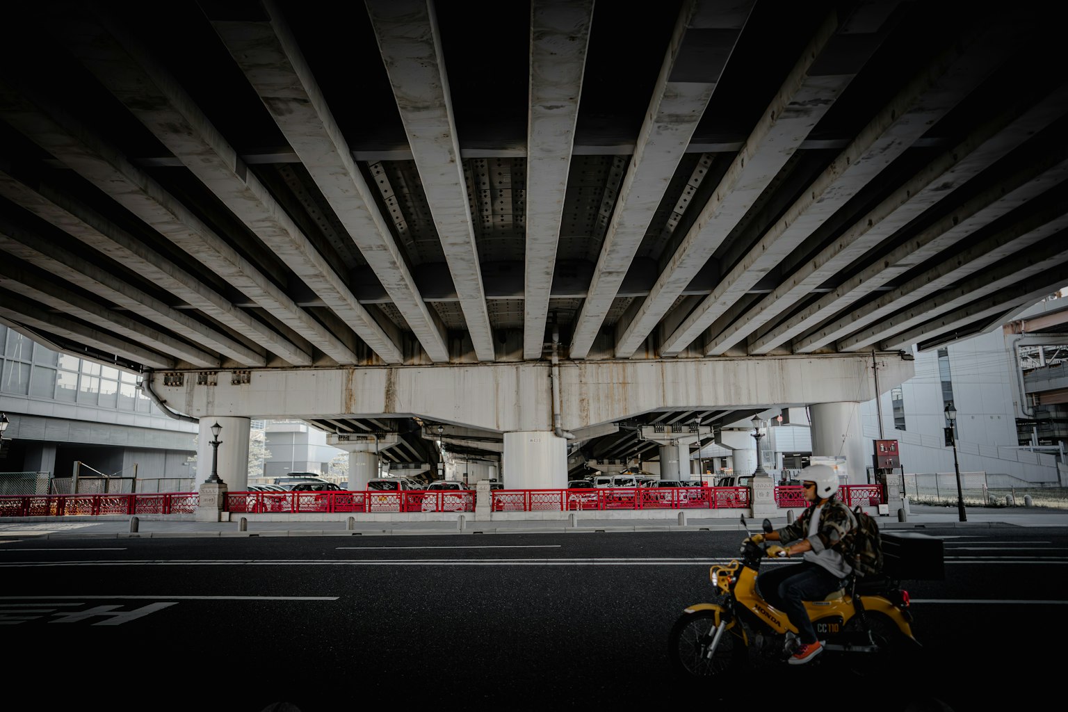 Vista desde debajo de un paso elevado con una motocicleta en la carretera y estructuras de concreto