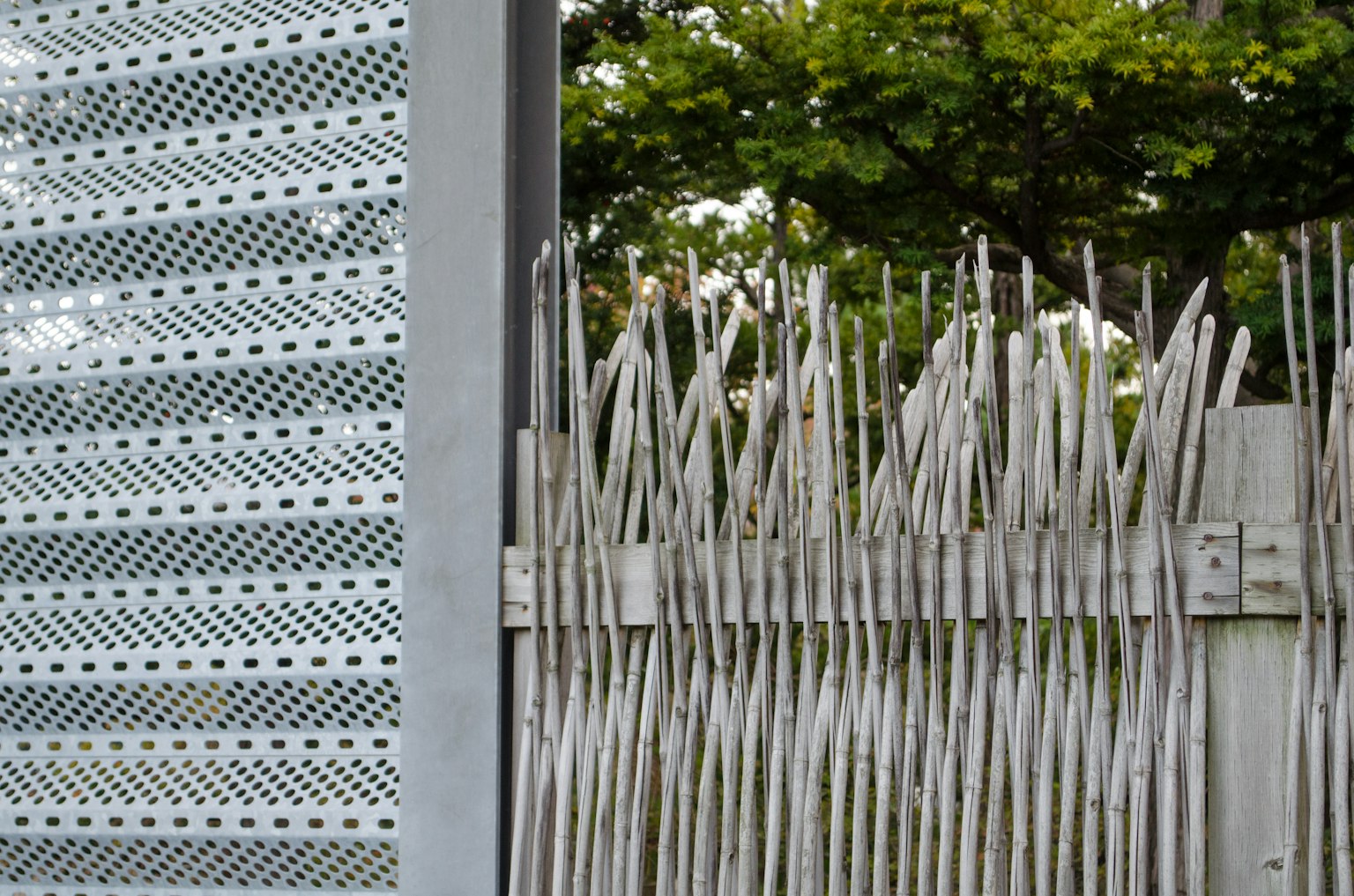 Metal panel and wooden fence creating a contrast with greenery