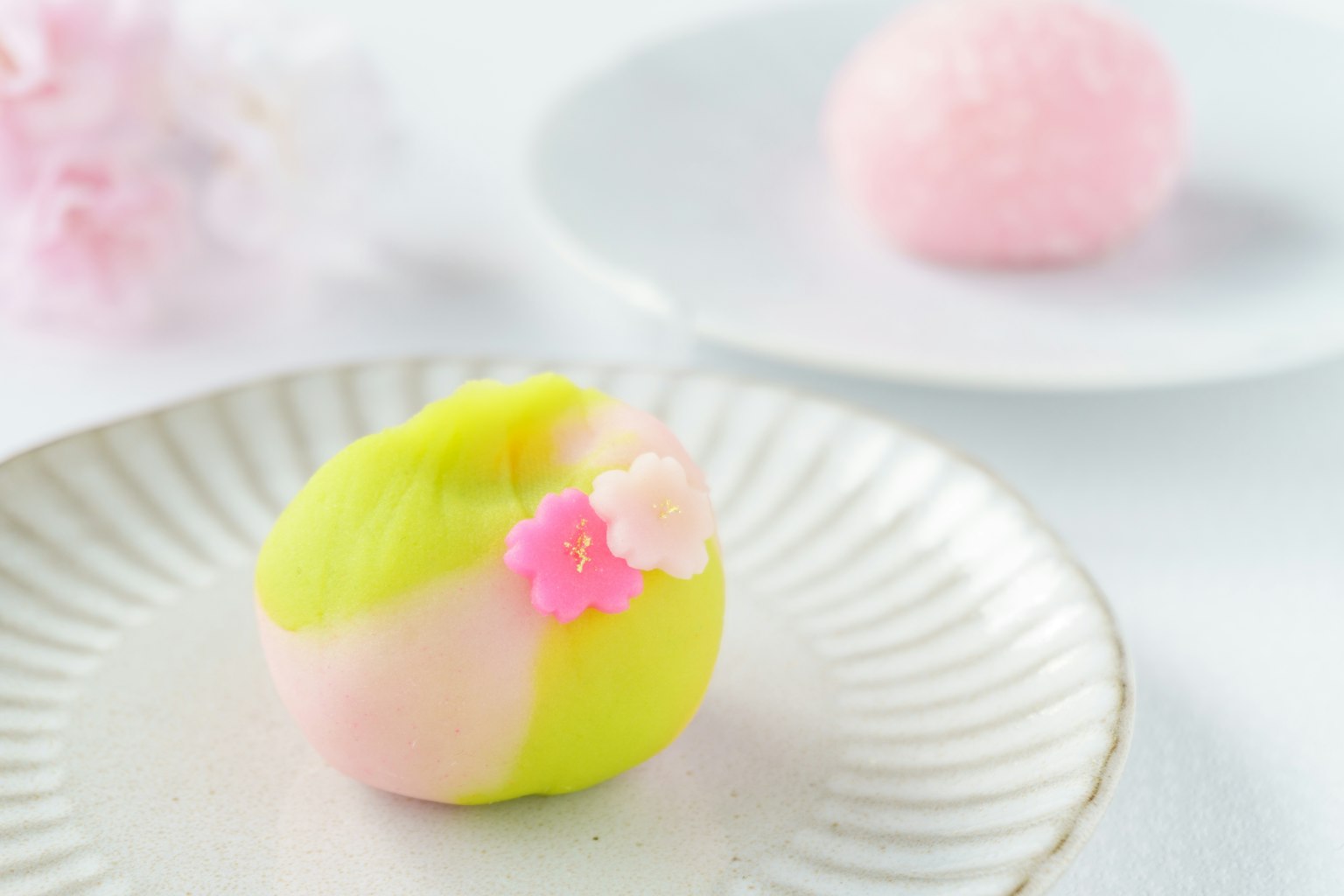 ขนมญี่ปุ่นสวยงามที่มีการออกแบบสีเขียวและชมพูประดับด้วยดอกไม้