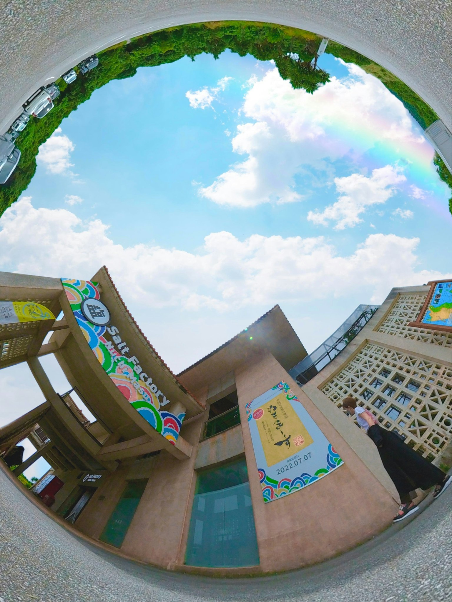 Mural berwarna di gedung dengan pelangi di langit biru