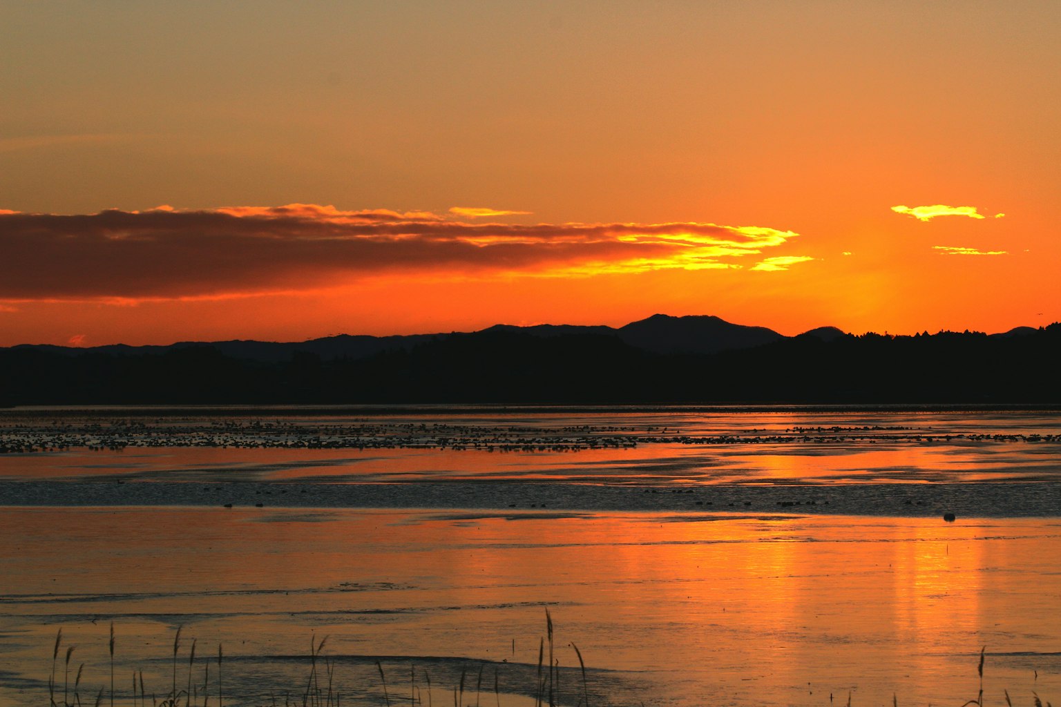 Beautiful sunset over a lake with silhouetted mountains
