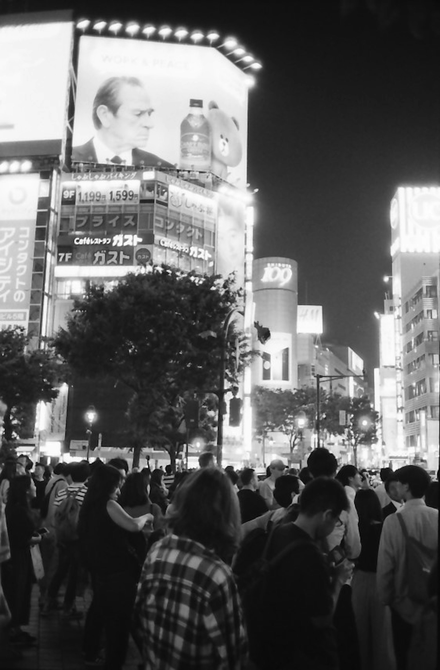 Folla che si raduna a Shibuya di notte con edifici luminosi e pubblicità