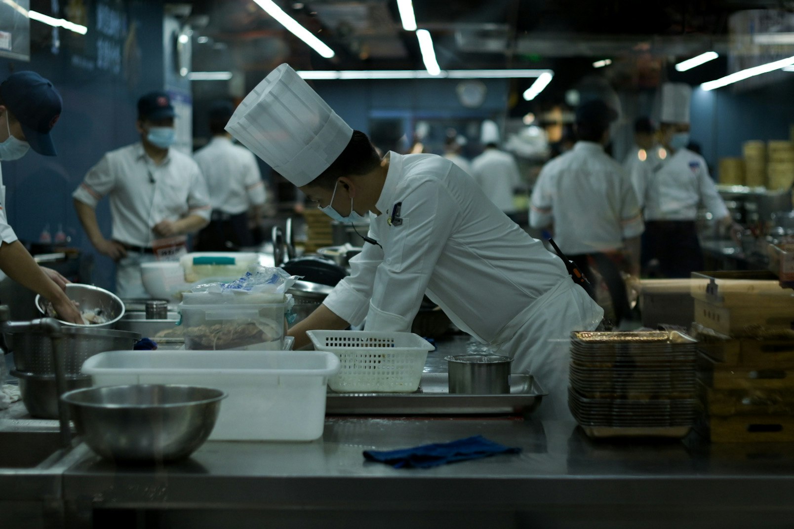 厨房で調理器具を扱う料理人たちの作業風景